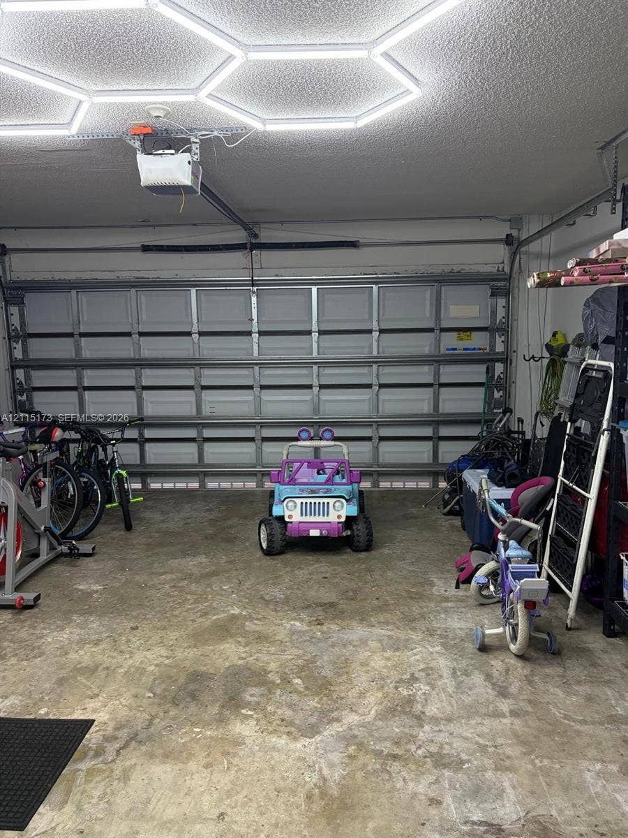 Garage space featuring a paneled sectional door, concrete flooring, and an installed hexagonal LED ceiling light fixture