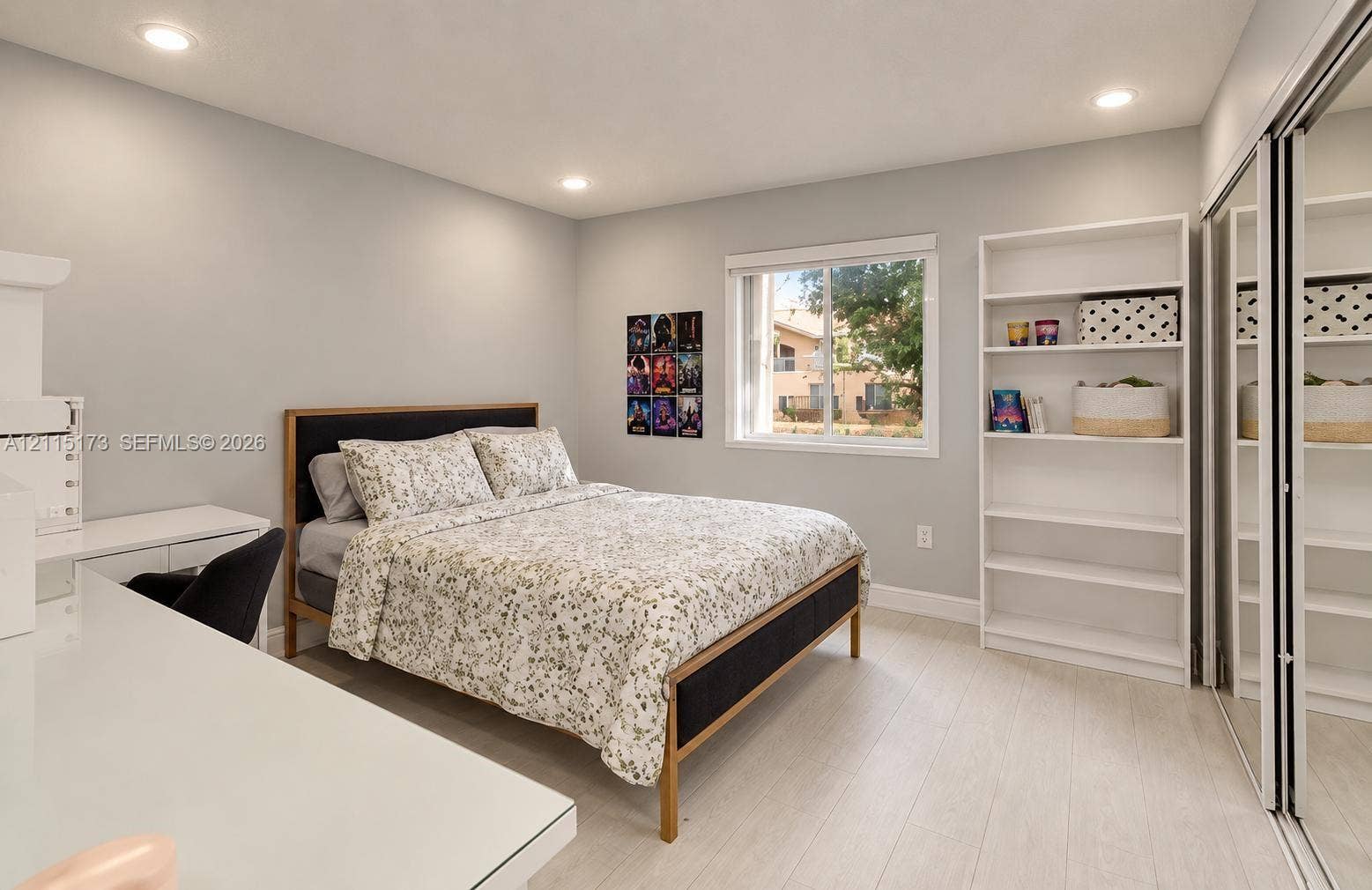 Room featuring wood-finish flooring, recessed lighting, a single-hung window, built-in shelving, and a dual-panel mirrored sliding closet