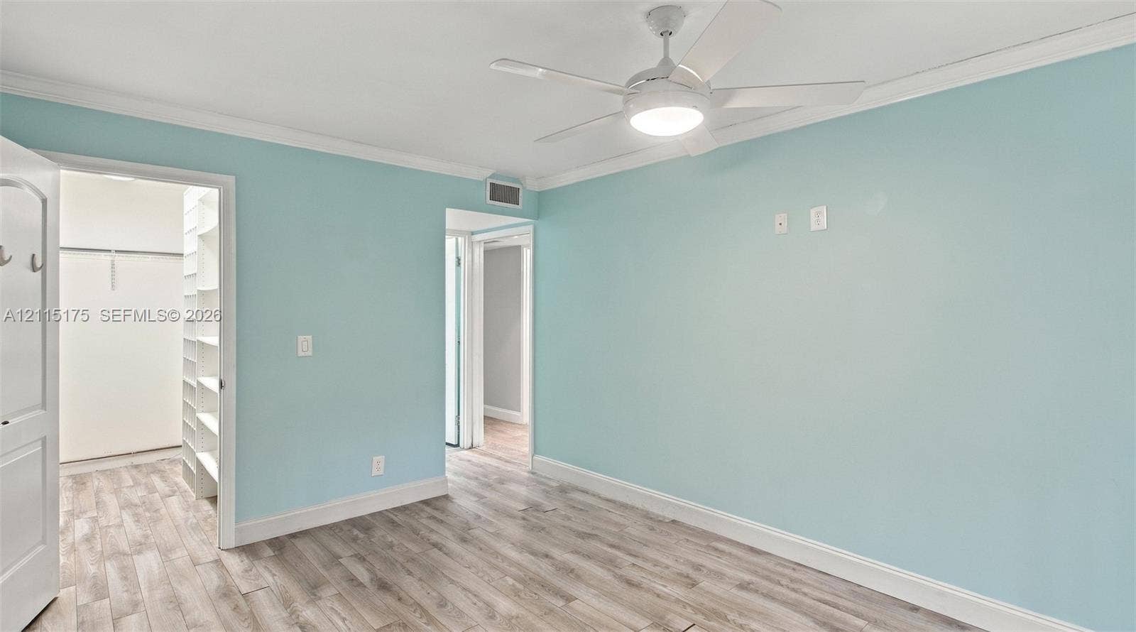 324 Seville N, Delray Beach, FL 33446 Room featuring wood-finish flooring, crown molding, a ceiling fan with integrated lighting, and a walk-in closet with built-in shelving
