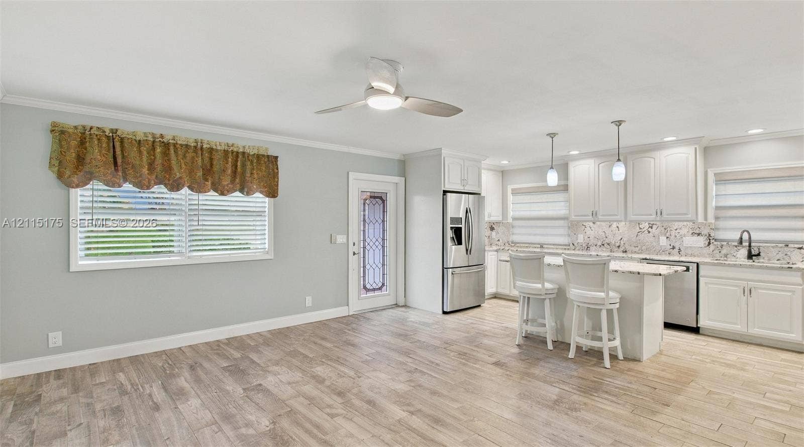 324 Seville N, Delray Beach, FL 33446 Open-concept interior featuring wood-finish tile flooring, white shaker-style cabinetry, stone-finish countertops, stainless steel appliances, and ceiling-mounted lighting