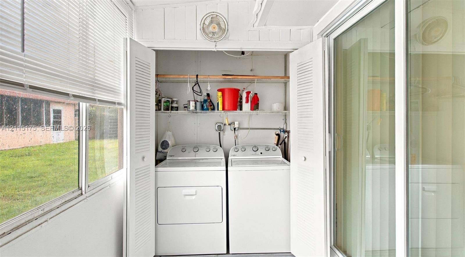 324 Seville N, Delray Beach, FL 33446 Laundry area featuring louvered bi-fold closet doors and wall-mounted shelving