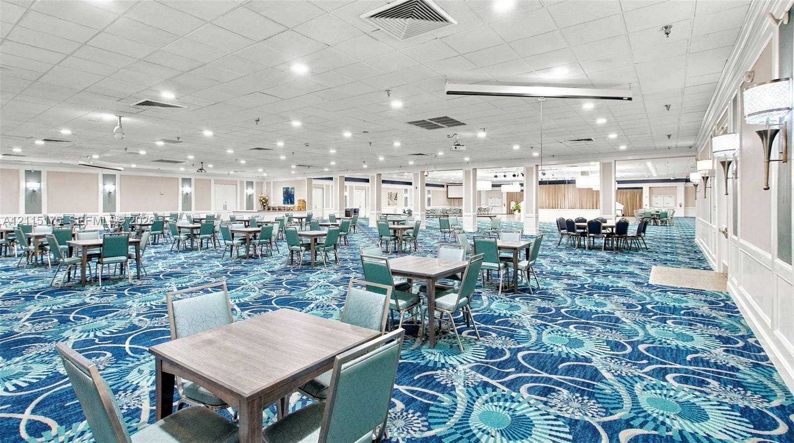 324 Seville N, Delray Beach, FL 33446 Expansive open-concept room featuring a dance floor, multiple tables, recessed lighting, wall-mounted sconce fixtures, and patterned carpeting for parties and special events