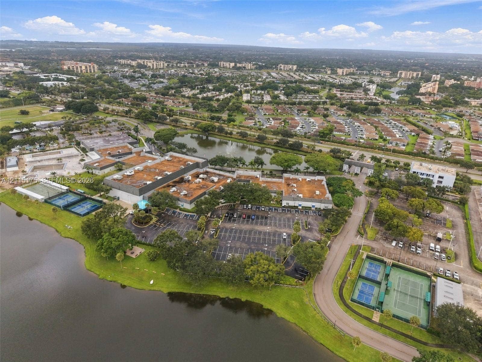 324 Seville N, Delray Beach, FL 33446 Aerial perspective of the property featuring dual tennis court facilities, expansive waterfront acreage, mature landscaping, and dedicated paved parking areas