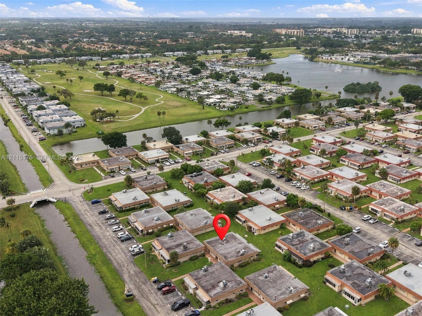 324 Seville N, Delray Beach, FL 33446 Aerial perspective of a single-story residence situated within a planned community, featuring a flat roof and proximity to a waterway and expansive green space