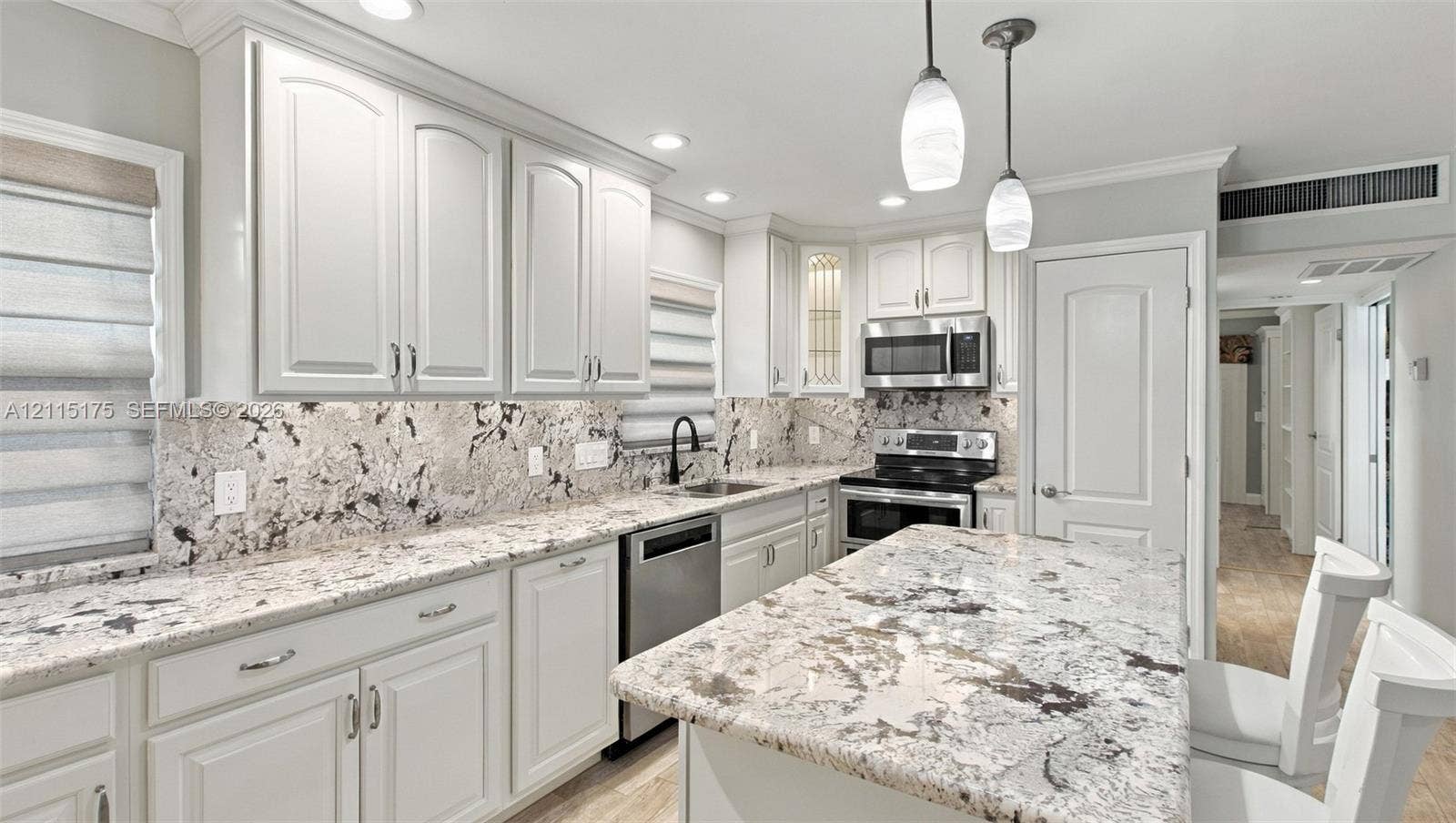 324 Seville N, Delray Beach, FL 33446 Open-concept kitchen featuring white shaker-style cabinetry, quartz countertops, stainless steel appliances, pendant lighting, and porcelain tile wood-look flooring