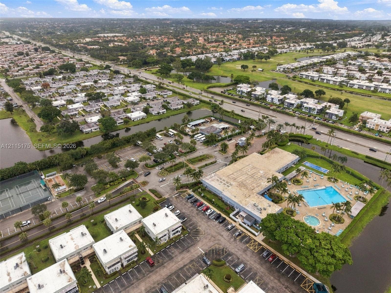 324 Seville N, Delray Beach, FL 33446 Aerial perspective featuring a swimming pool, multiple tennis courts, paved parking areas, and mature landscaping