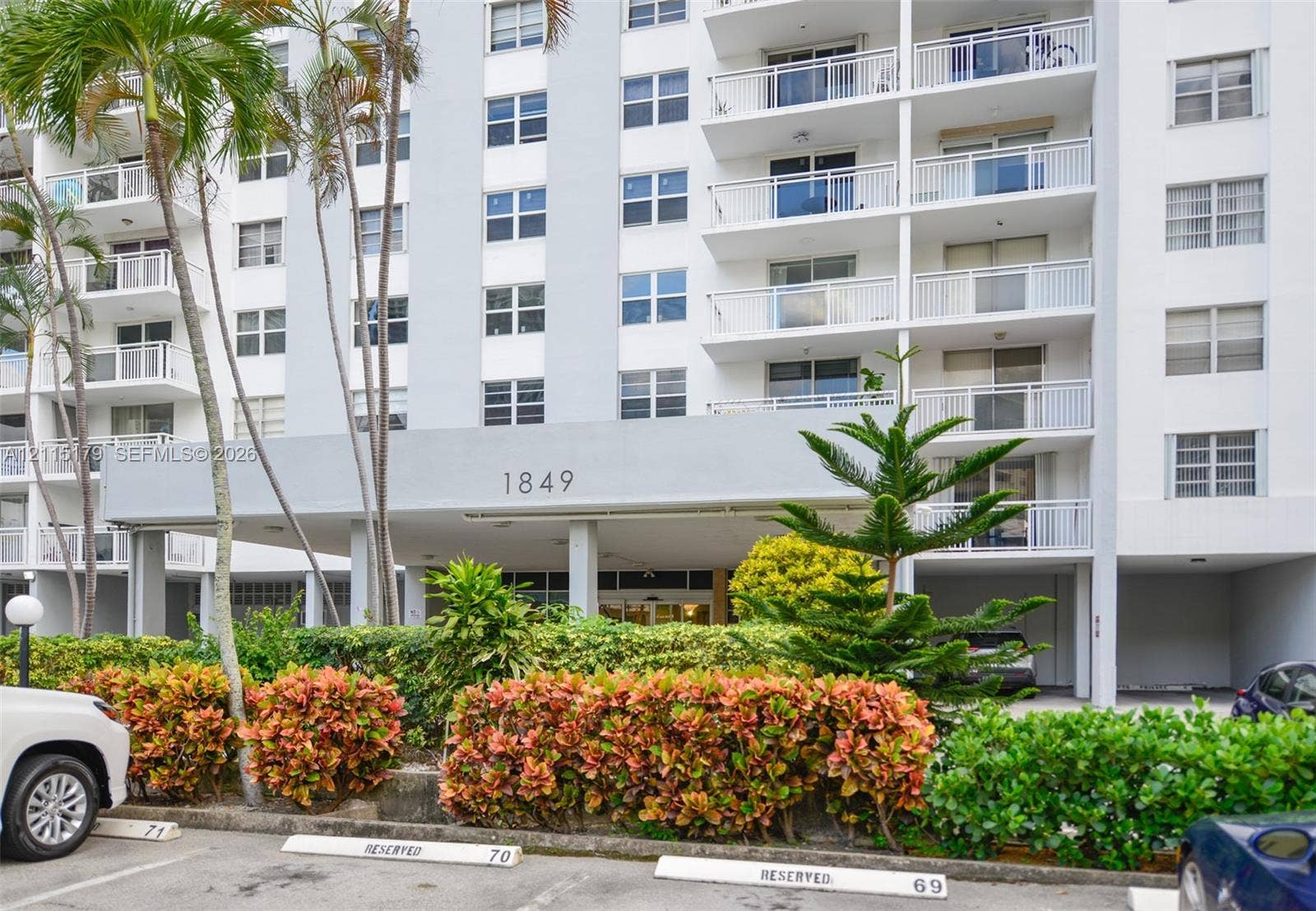 1849 S Ocean Drive, #407, Hallandale Beach, Hallandale Beach, FL 33009 Multi-story residential exterior featuring private balconies with railings, a covered entrance canopy, and established exterior landscaping