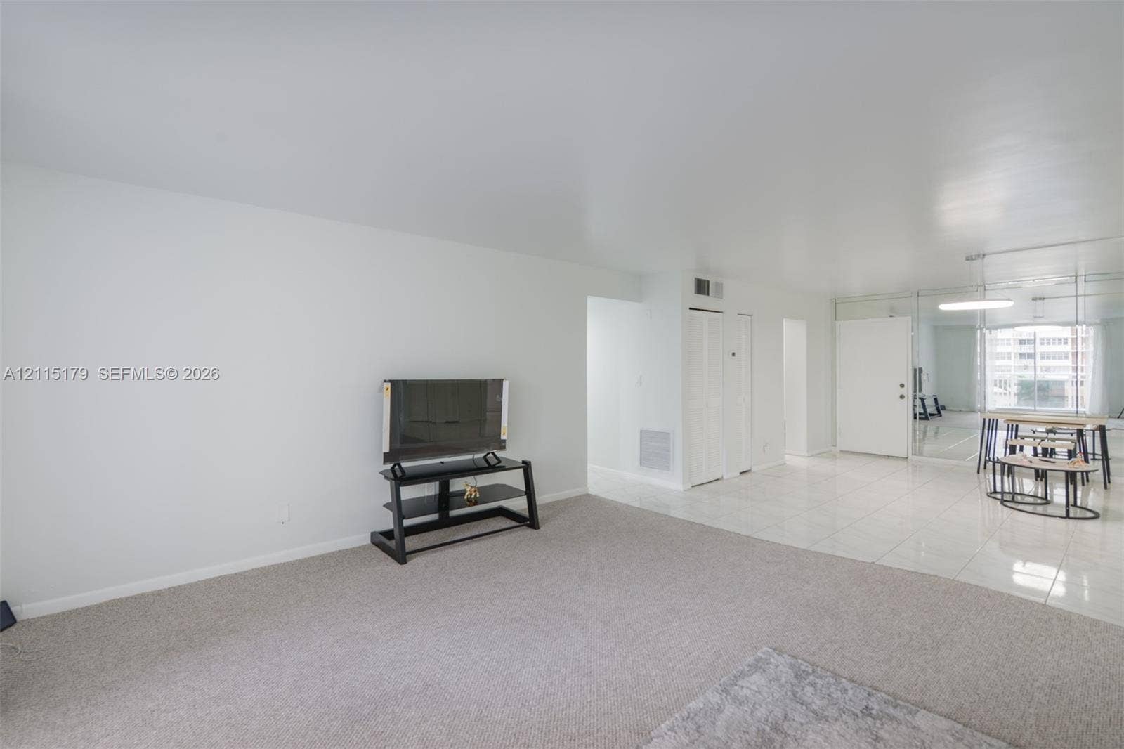 1849 S Ocean Drive, #407, Hallandale Beach, Hallandale Beach, FL 33009 Interior space featuring light-toned carpeting, reflective tile flooring, and a mirrored wall panel