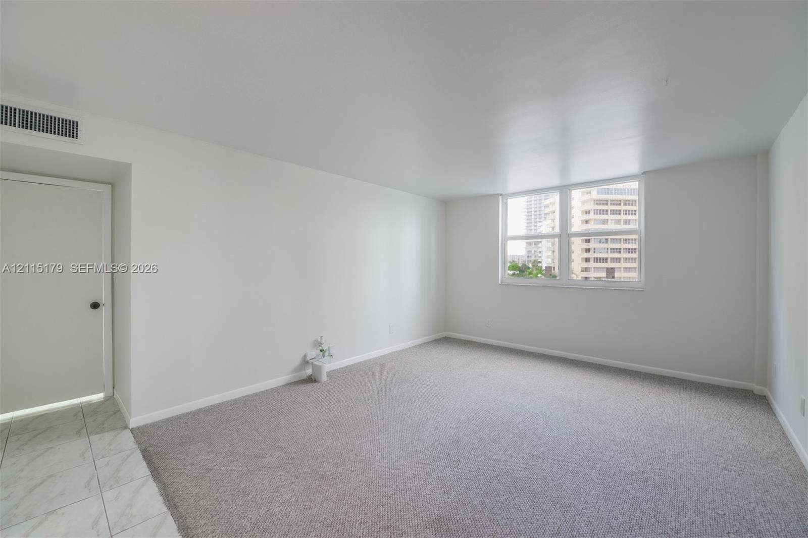 1849 S Ocean Drive, #407, Hallandale Beach, Hallandale Beach, FL 33009 Neutral-toned interior space featuring light-colored wall-to-wall carpeting, white walls, and a large multi-pane window