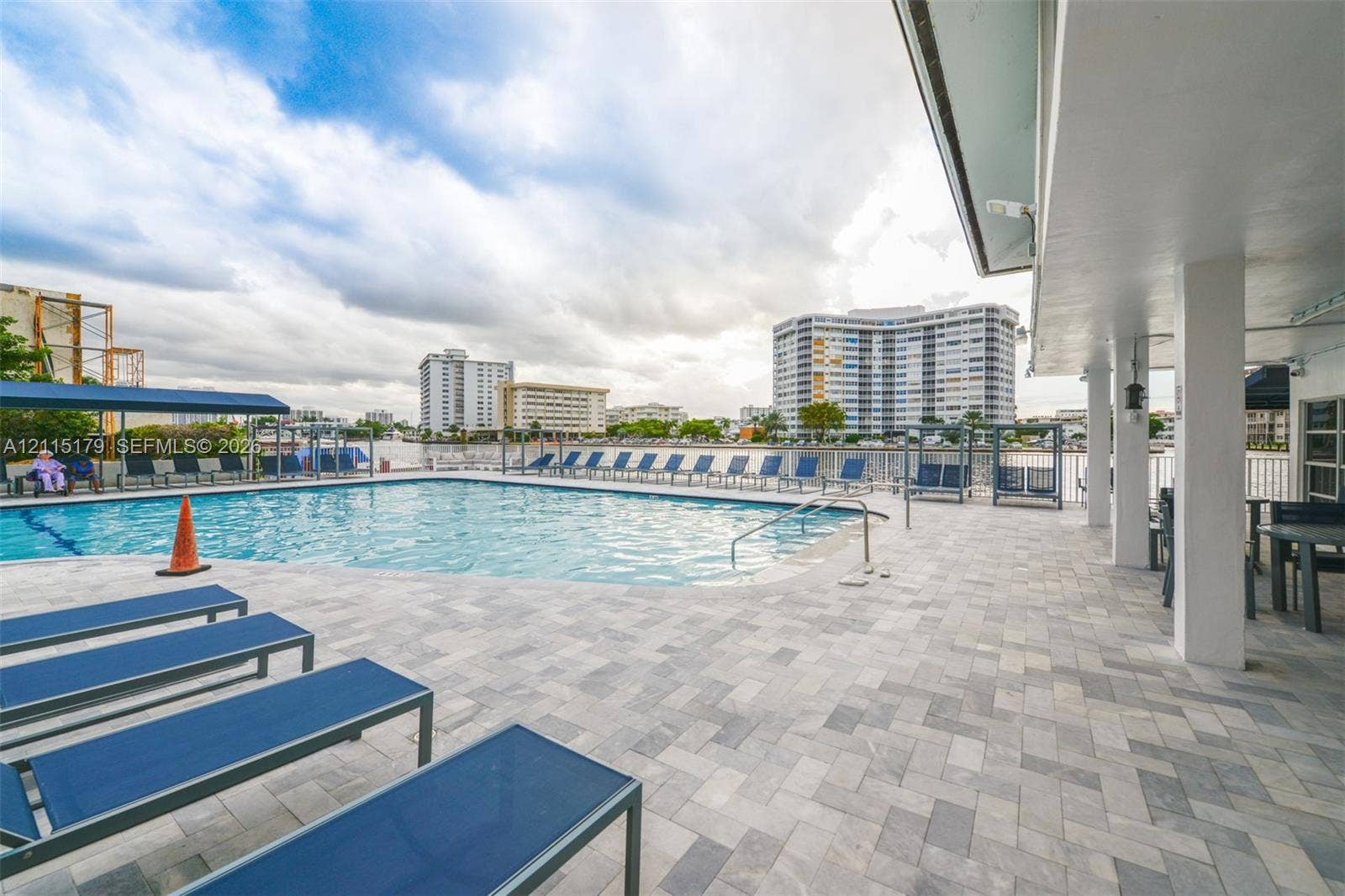 1849 S Ocean Drive, #407, Hallandale Beach, Hallandale Beach, FL 33009 In-ground swimming pool featuring a herringbone-patterned stone paver deck and a covered patio area