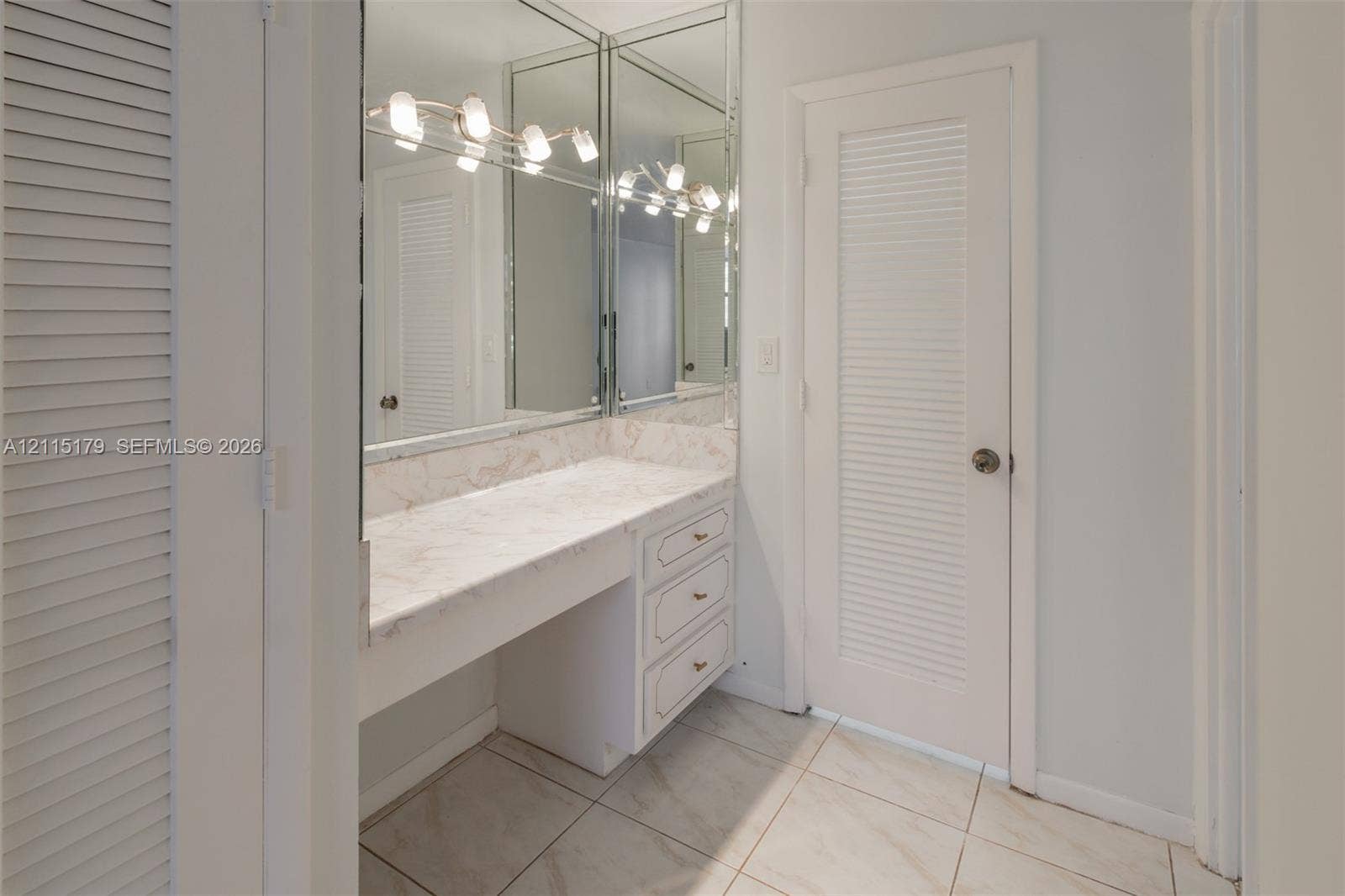 1849 S Ocean Drive, #407, Hallandale Beach, Hallandale Beach, FL 33009 Built-in vanity with stone-surfaced countertop, three-drawer cabinetry, full-height wall mirrors, five-bulb integrated light fixture, and louvered doors