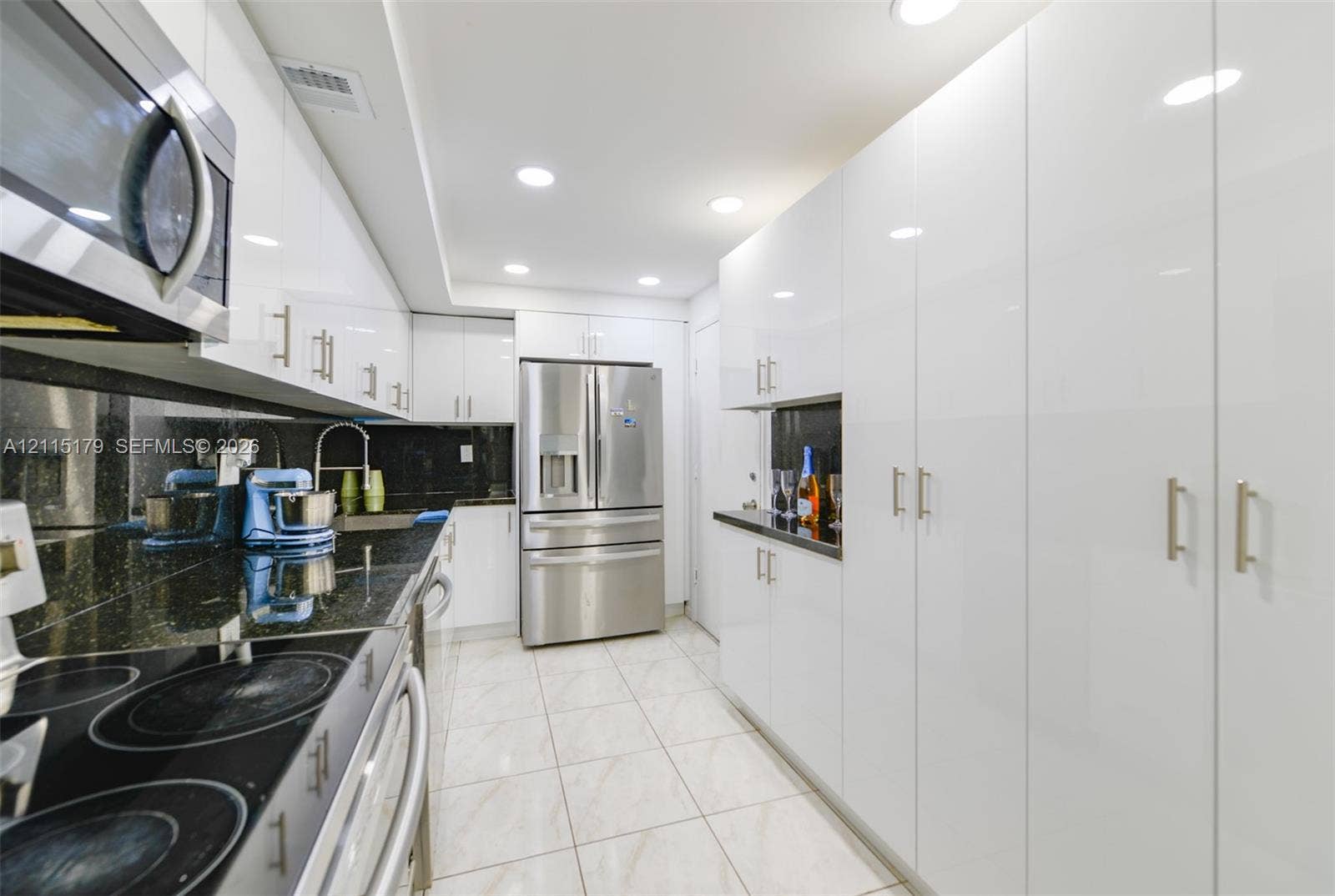 1849 S Ocean Drive, #407, Hallandale Beach, Hallandale Beach, FL 33009 Galley kitchen featuring high-gloss white cabinetry, stainless steel appliances, dark stone countertops, tile flooring, and recessed ceiling lighting