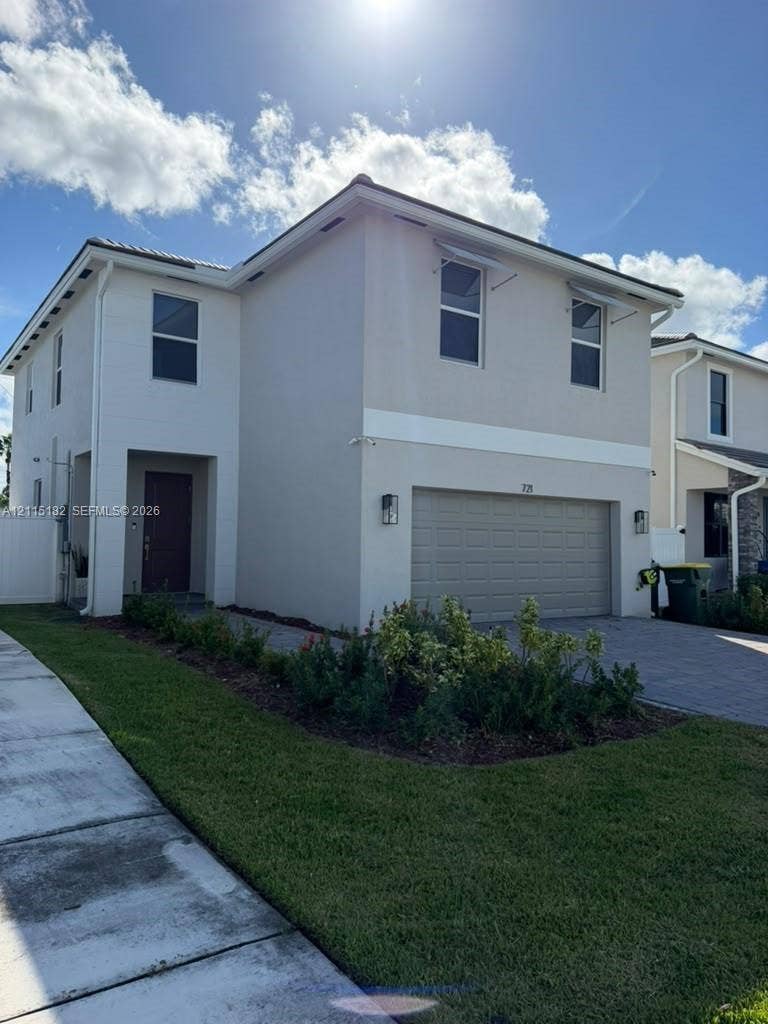 721 SE 17th Avenue, #721, Homestead, Homestead, FL 33033 Two-story stucco exterior featuring a paver driveway, an integrated two-car garage, and manicured landscaping