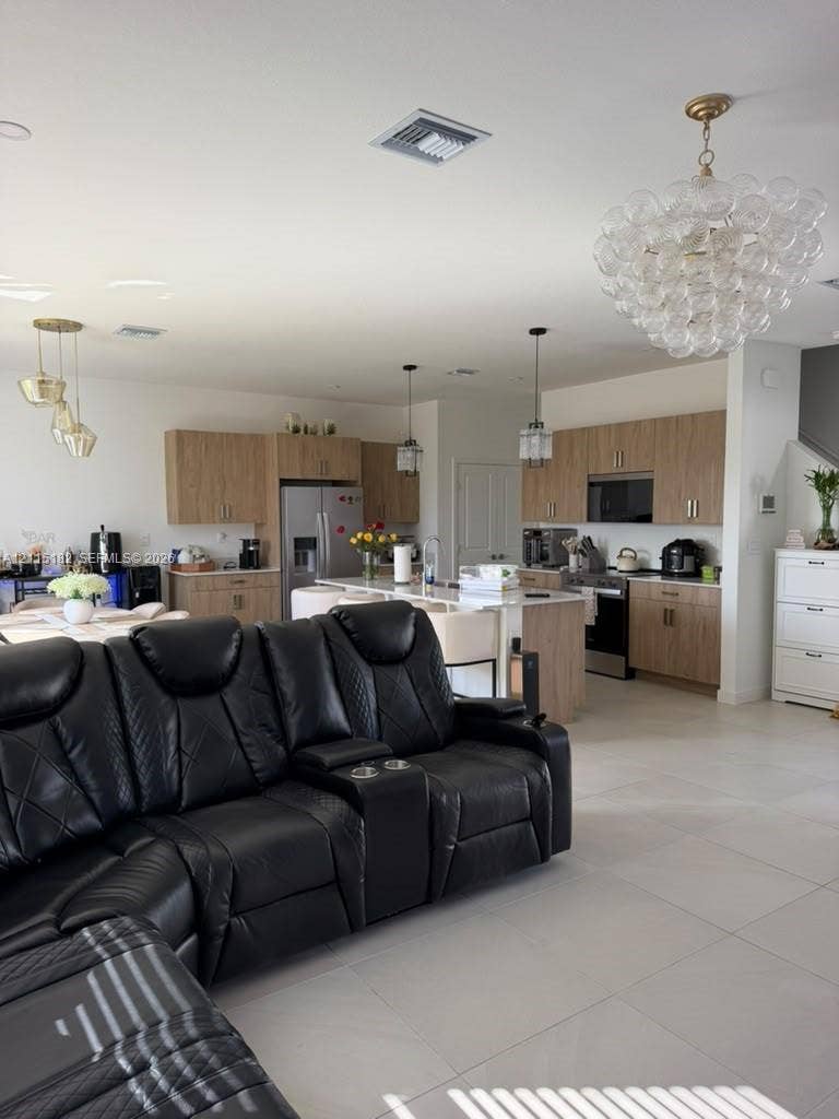 721 SE 17th Avenue, #721, Homestead, Homestead, FL 33033 Kitchen featuring wood-finish cabinetry, a large central island with a stone-top counter, stainless steel appliances, large-format tile flooring, and decorative glass chandeliers