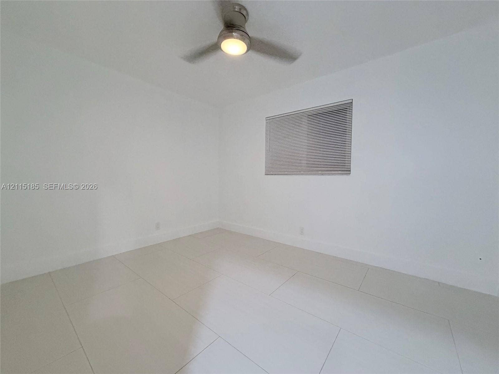 105-107 NE 30th Court, Wilton Manors, FL 33334 Neutral interior featuring white walls, large-format tile flooring, and a ceiling fan with integrated lighting