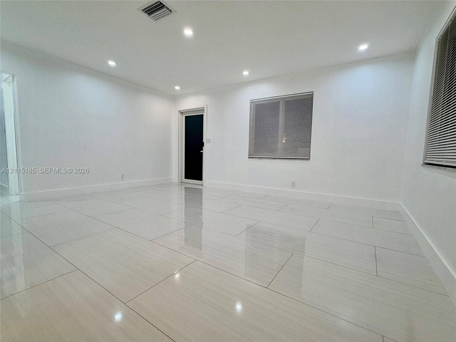 105-107 NE 30th Court, Wilton Manors, FL 33334 Interior space featuring large-format polished tile flooring, recessed LED ceiling lighting, and a neutral color palette