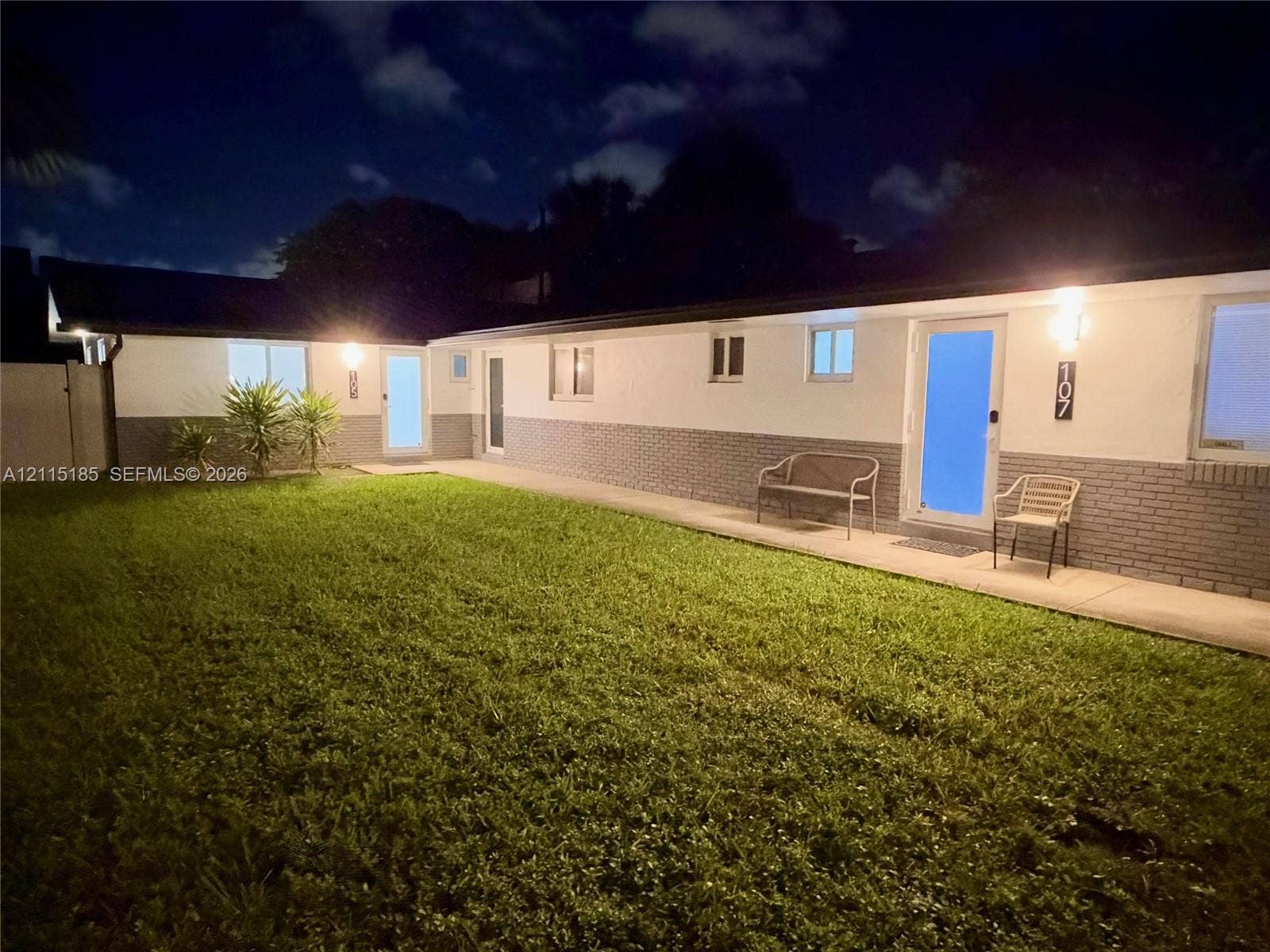 105-107 NE 30th Court, Wilton Manors, FL 33334 Single-story exterior featuring two-tone masonry and stucco facade, concrete walkway, and manicured lawn