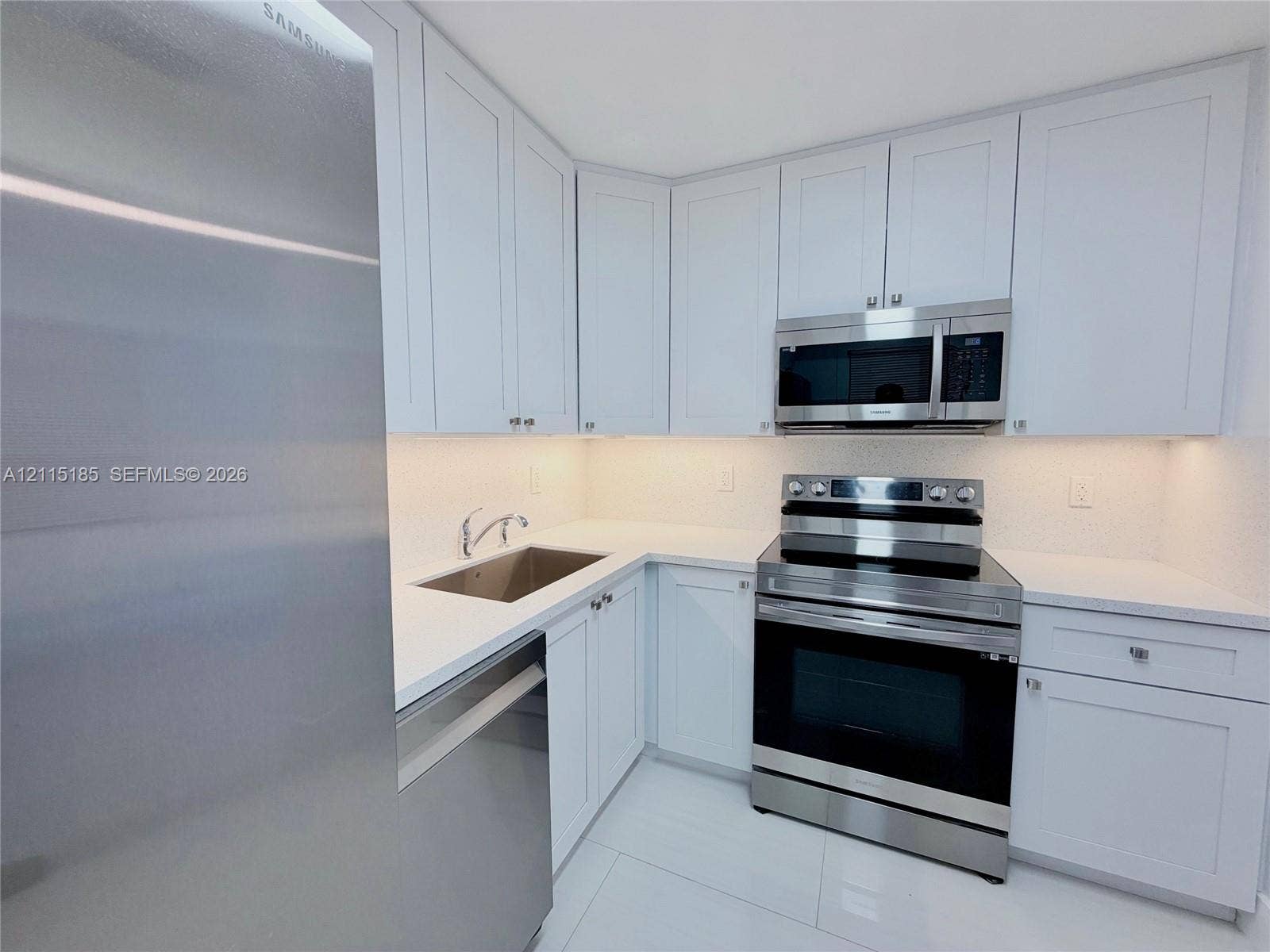 105-107 NE 30th Court, Wilton Manors, FL 33334 Kitchen featuring white shaker-style cabinetry, stainless steel appliances, white solid-surface countertops, and undermount stainless steel sink