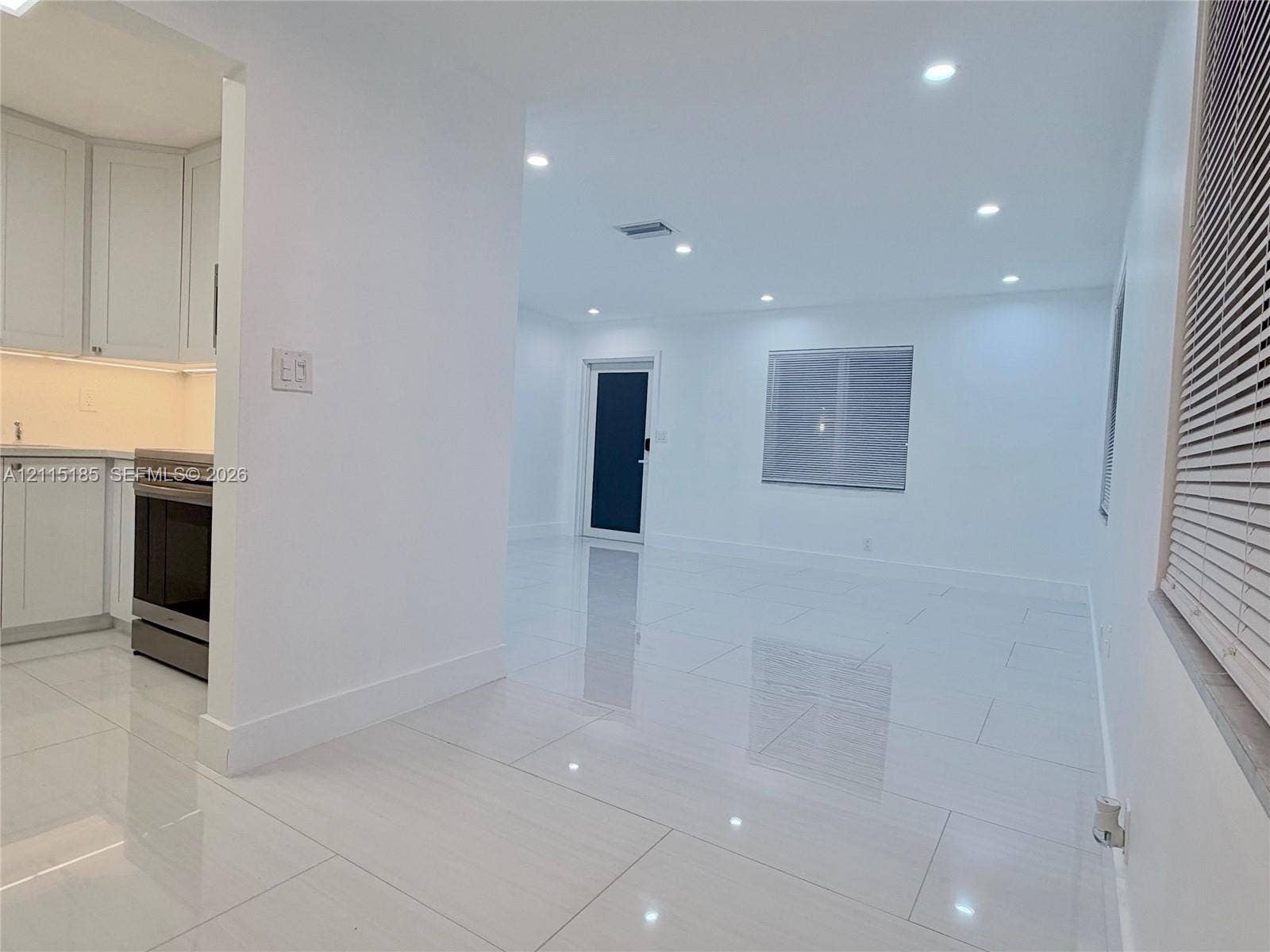 105-107 NE 30th Court, Wilton Manors, FL 33334 Open interior featuring large-format ceramic tile flooring, recessed ceiling lighting, white shaker-style cabinetry, and a dark-toned door