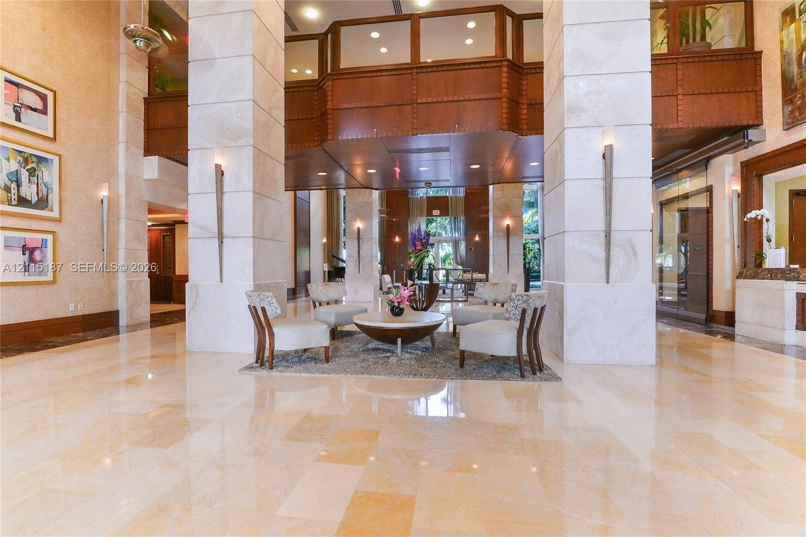 19501 W Country Club Drive, #504, Aventura, Aventura, FL 33180 Grand lobby featuring dual-story stone-clad pillars, polished stone flooring, intricate wood-panel trim, and recessed ceiling lighting