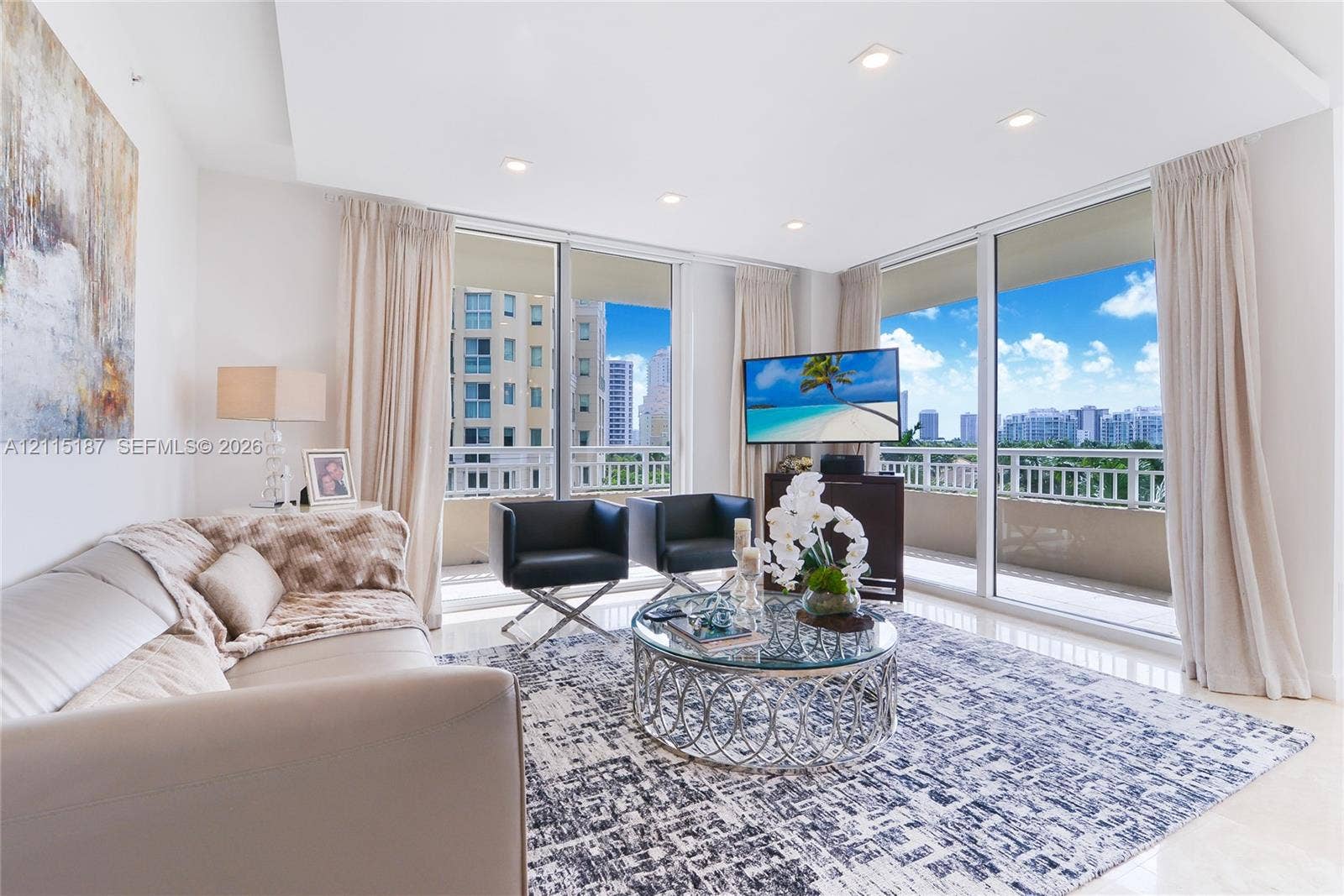 19501 W Country Club Drive, #504, Aventura, Aventura, FL 33180 Living area featuring a tray ceiling with recessed lighting, large-format tile flooring, and expansive floor-to-ceiling glass sliding doors providing access to a covered balcony with a glass railing