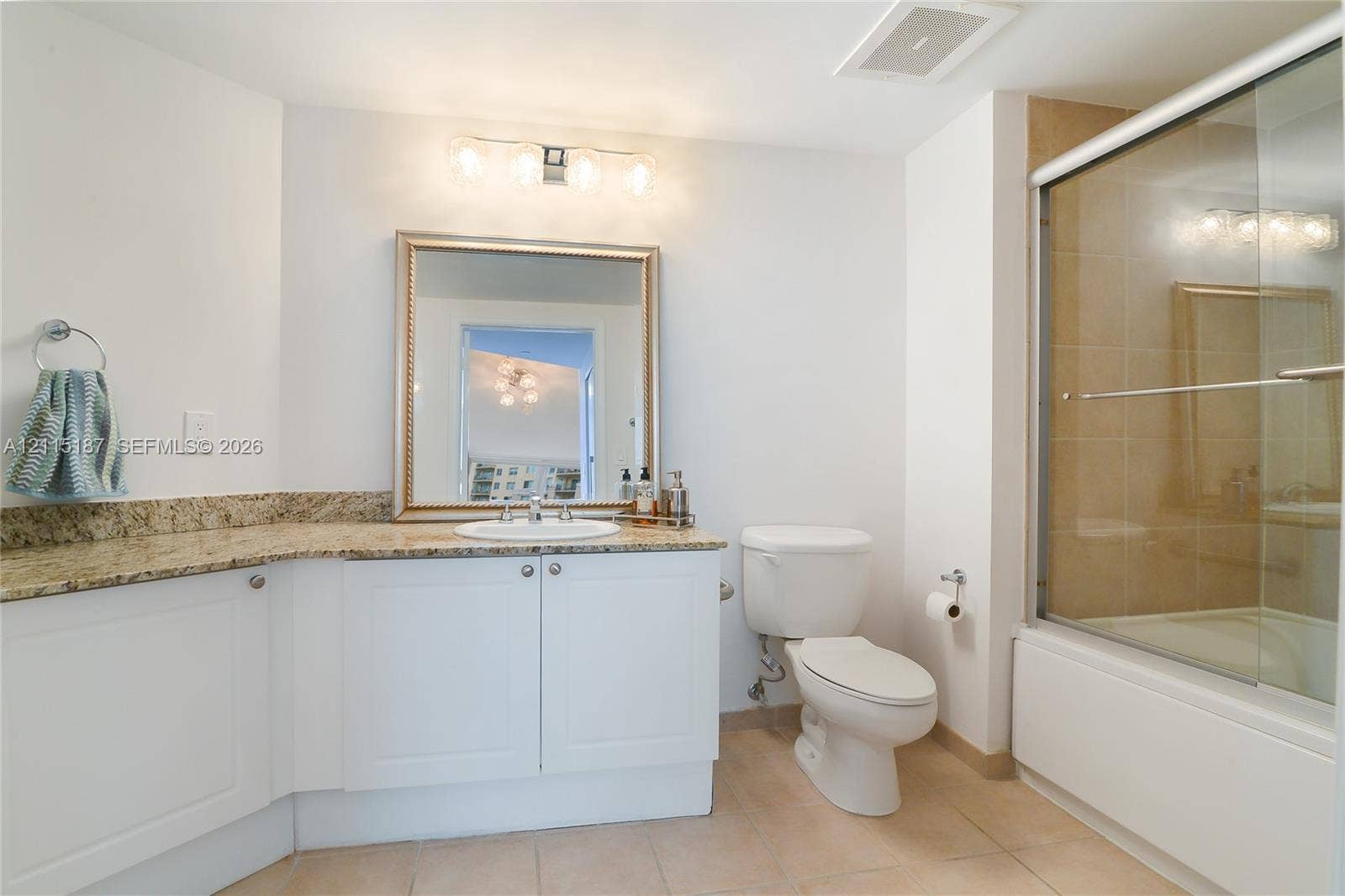 19501 W Country Club Drive, #504, Aventura, Aventura, FL 33180 Bathroom featuring white cabinetry, stone-surface countertop with an integrated basin, framed wall mirror, four-light vanity fixture, and a shower-tub combination with sliding glass doors