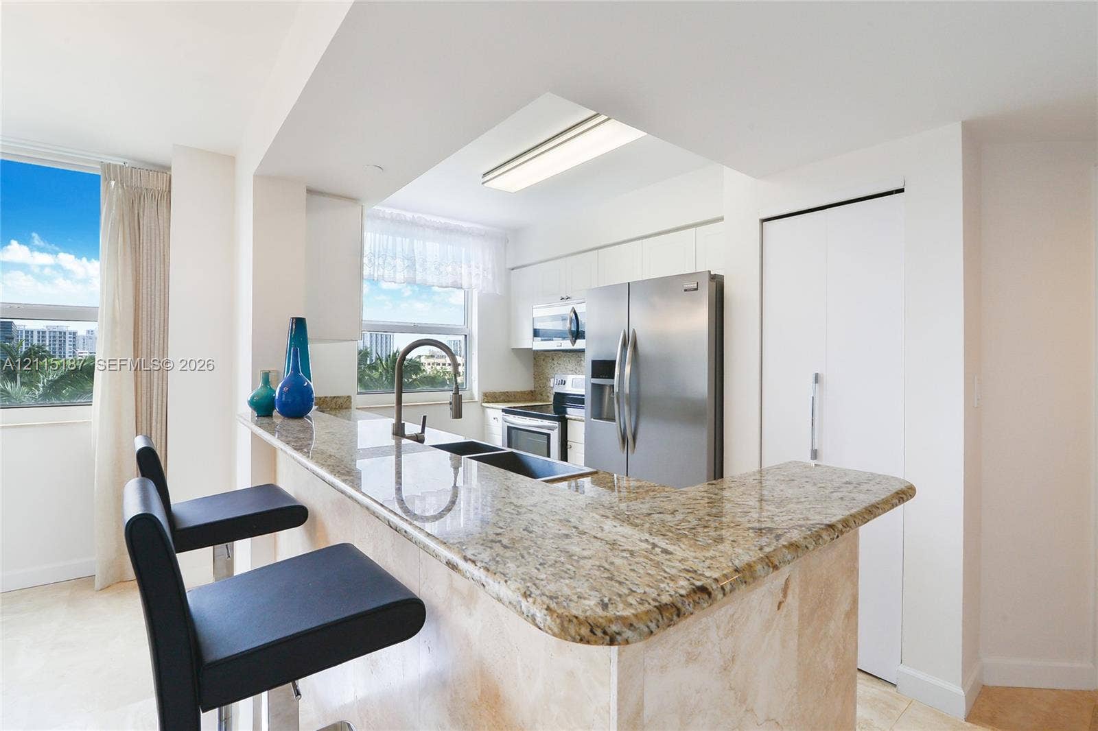 19501 W Country Club Drive, #504, Aventura, Aventura, FL 33180 Kitchen featuring a peninsula with a stone countertop, stainless steel refrigerator, built-in microwave, drop-in dual basin sink with gooseneck faucet, and flat-panel cabinetry