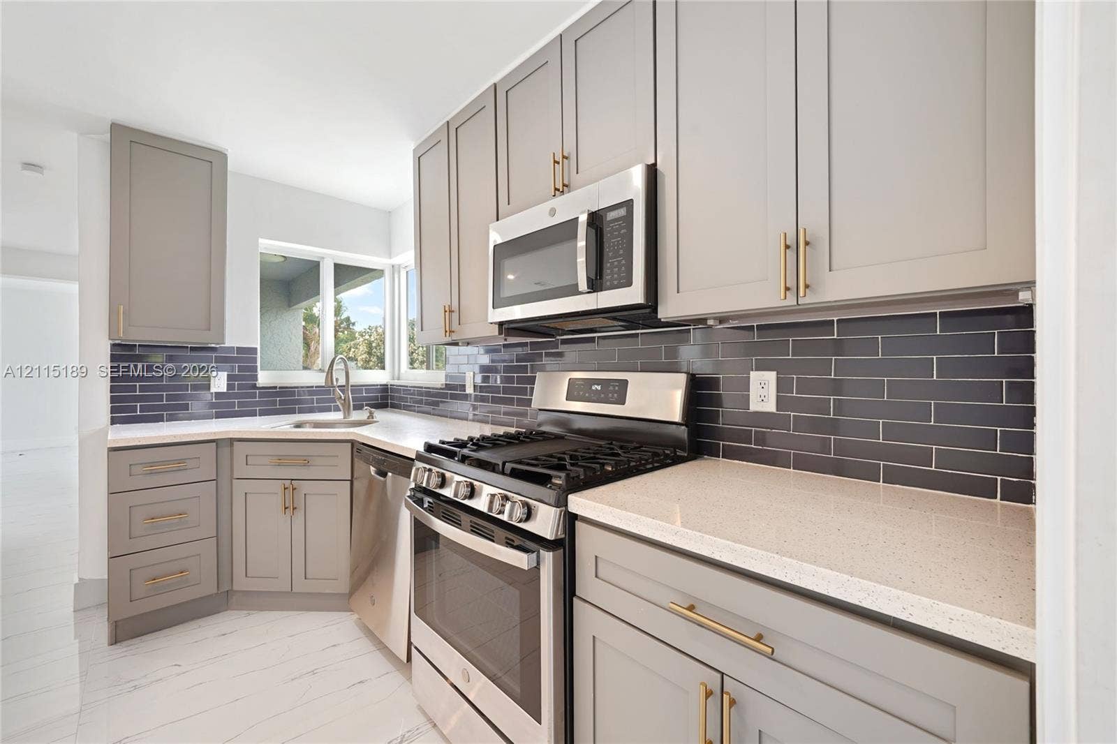2111 N 14th Court, Hollywood, Hollywood, FL 33020 Kitchen featuring shaker-style cabinetry with gold-tone hardware, polished solid surface countertops, dark subway tile backsplash, stainless steel appliances, and white wood-finish flooring