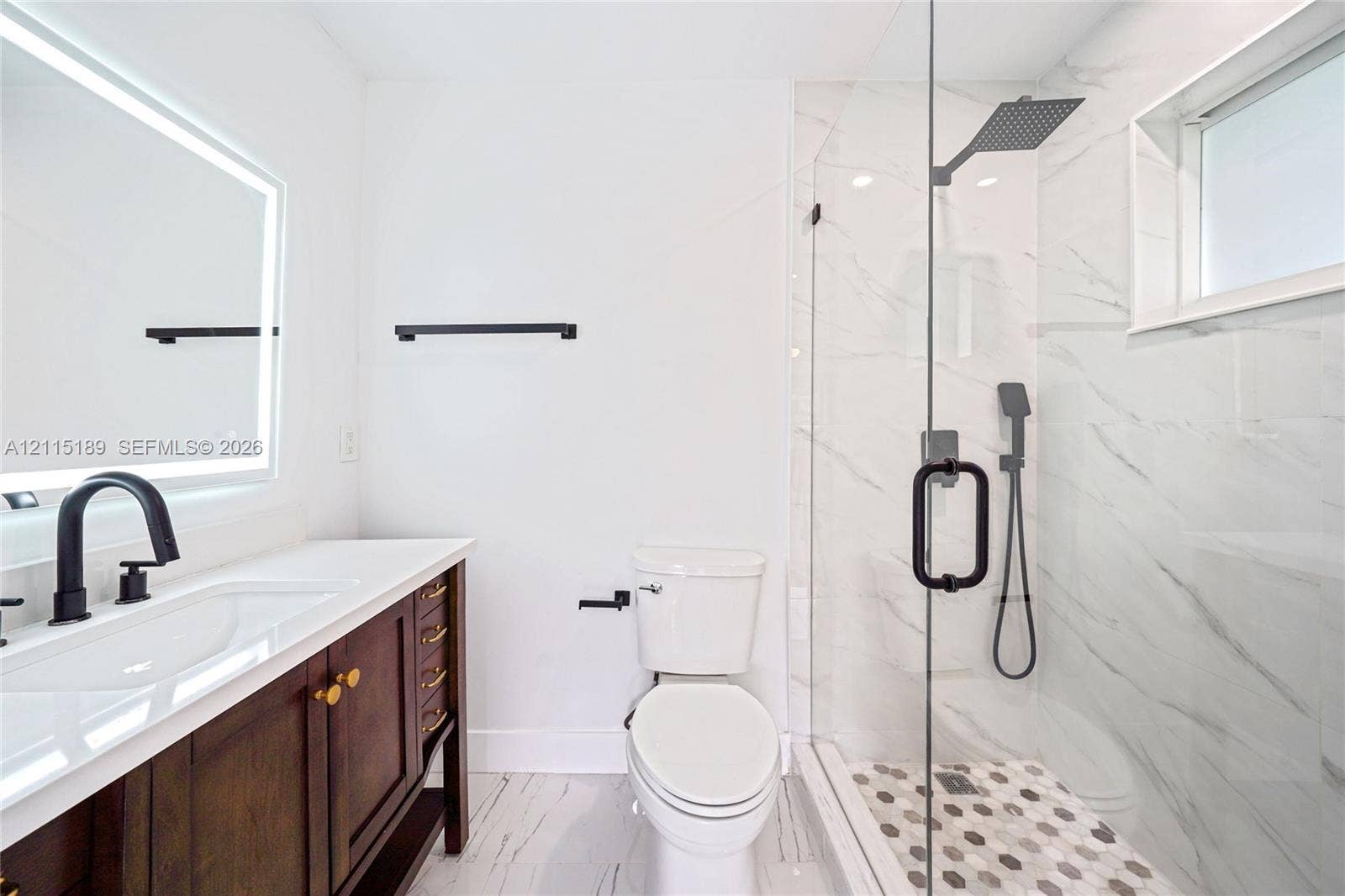 2111 N 14th Court, Hollywood, Hollywood, FL 33020 Bathroom featuring a dark wood vanity with a white countertop, backlit vanity mirror, walk-in shower with matte black fixtures, and patterned shower floor tile