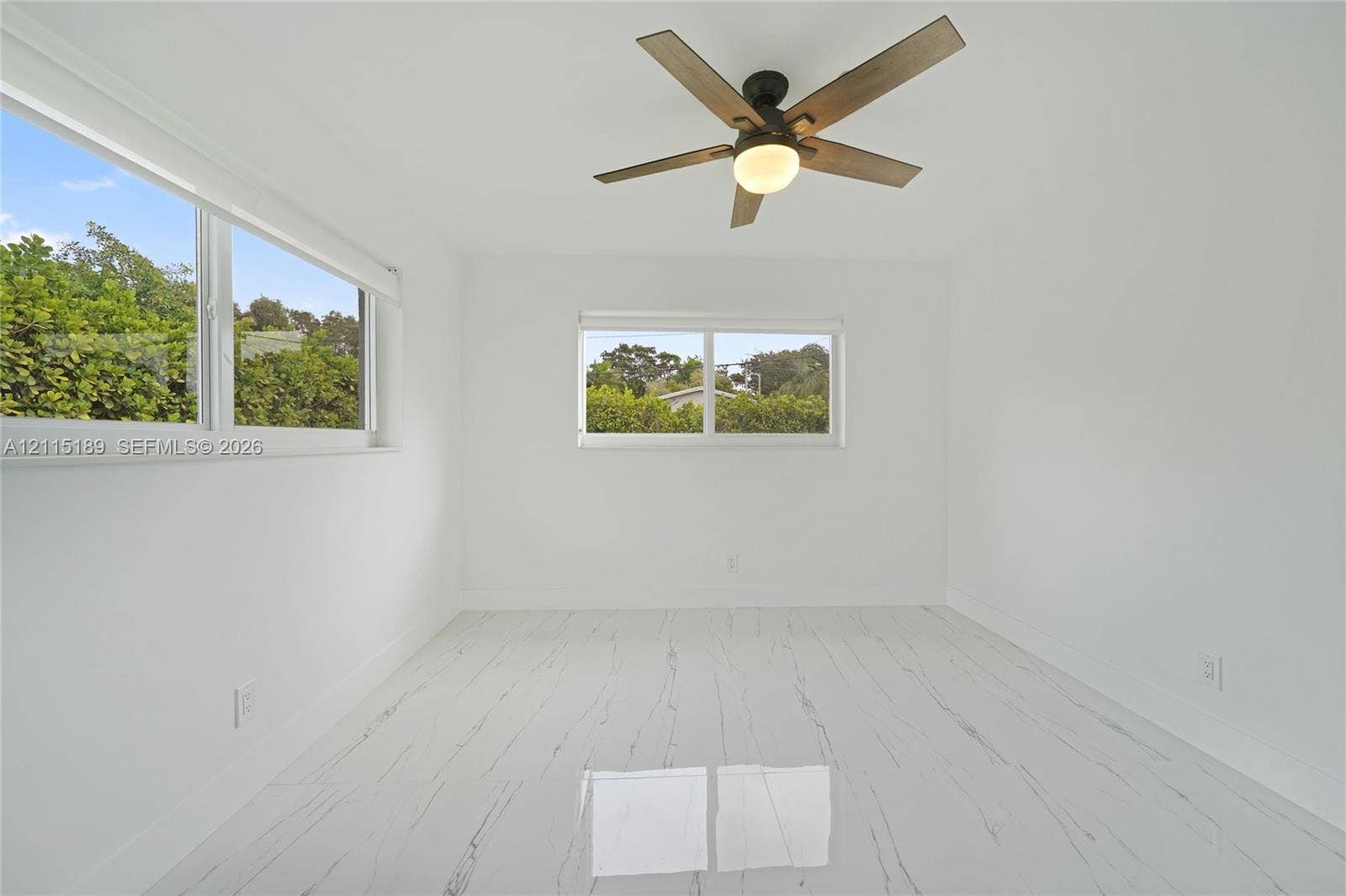 2111 N 14th Court, Hollywood, Hollywood, FL 33020 Room featuring white stone-finish flooring with grey veining, two horizontal sliding windows, and a ceiling-mounted fan with integrated light fixture