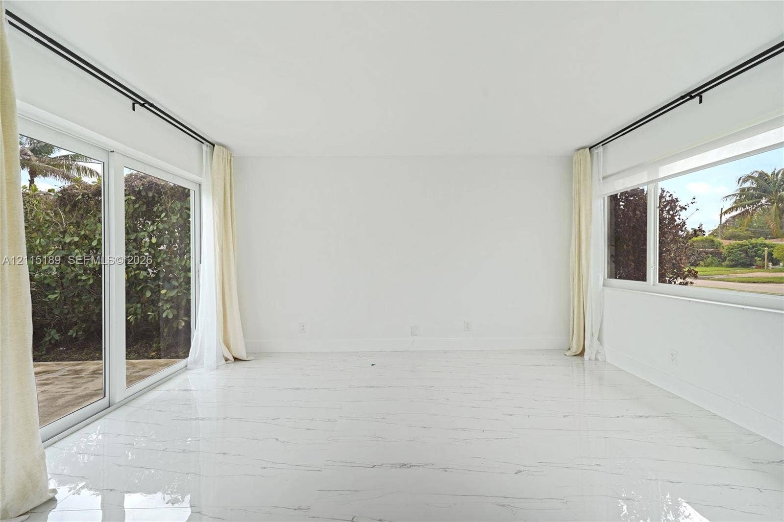 2111 N 14th Court, Hollywood, Hollywood, FL 33020 Bright room featuring white tile flooring with grey veining, expansive sliding glass doors, and large windows with black curtain hardware
