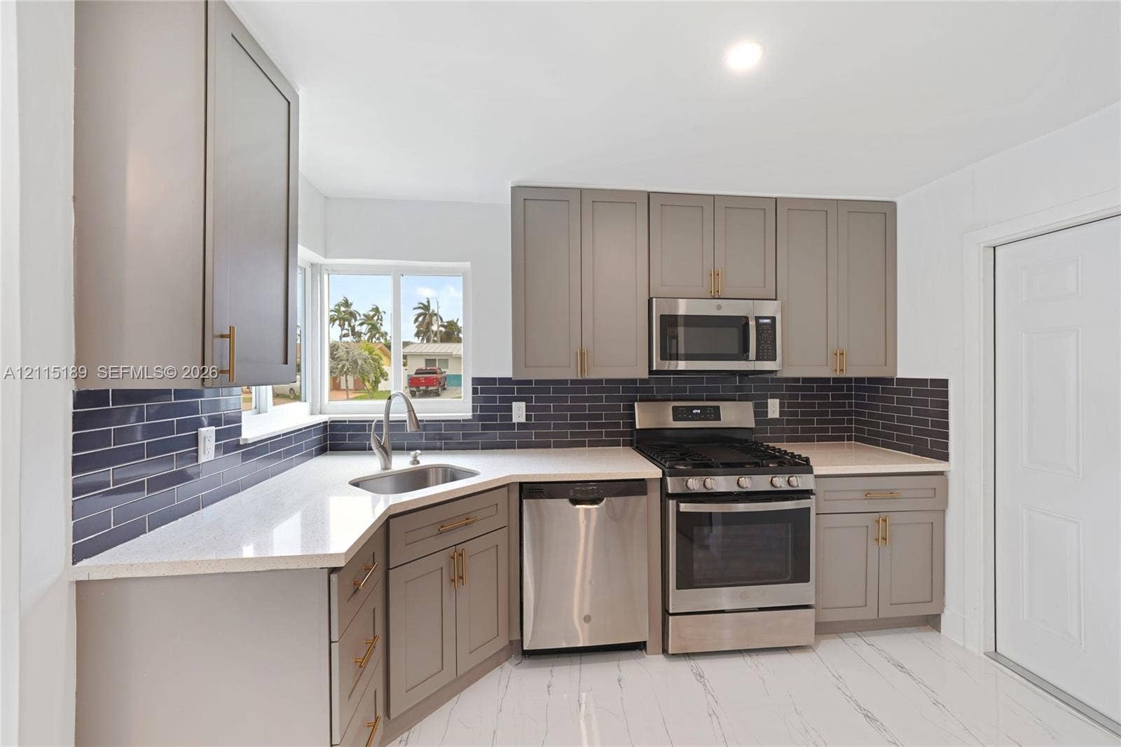 2111 N 14th Court, Hollywood, Hollywood, FL 33020 Kitchen featuring shaker-style cabinetry, dark tile backsplash, stainless steel appliances, light-toned countertops, and an undermount sink
