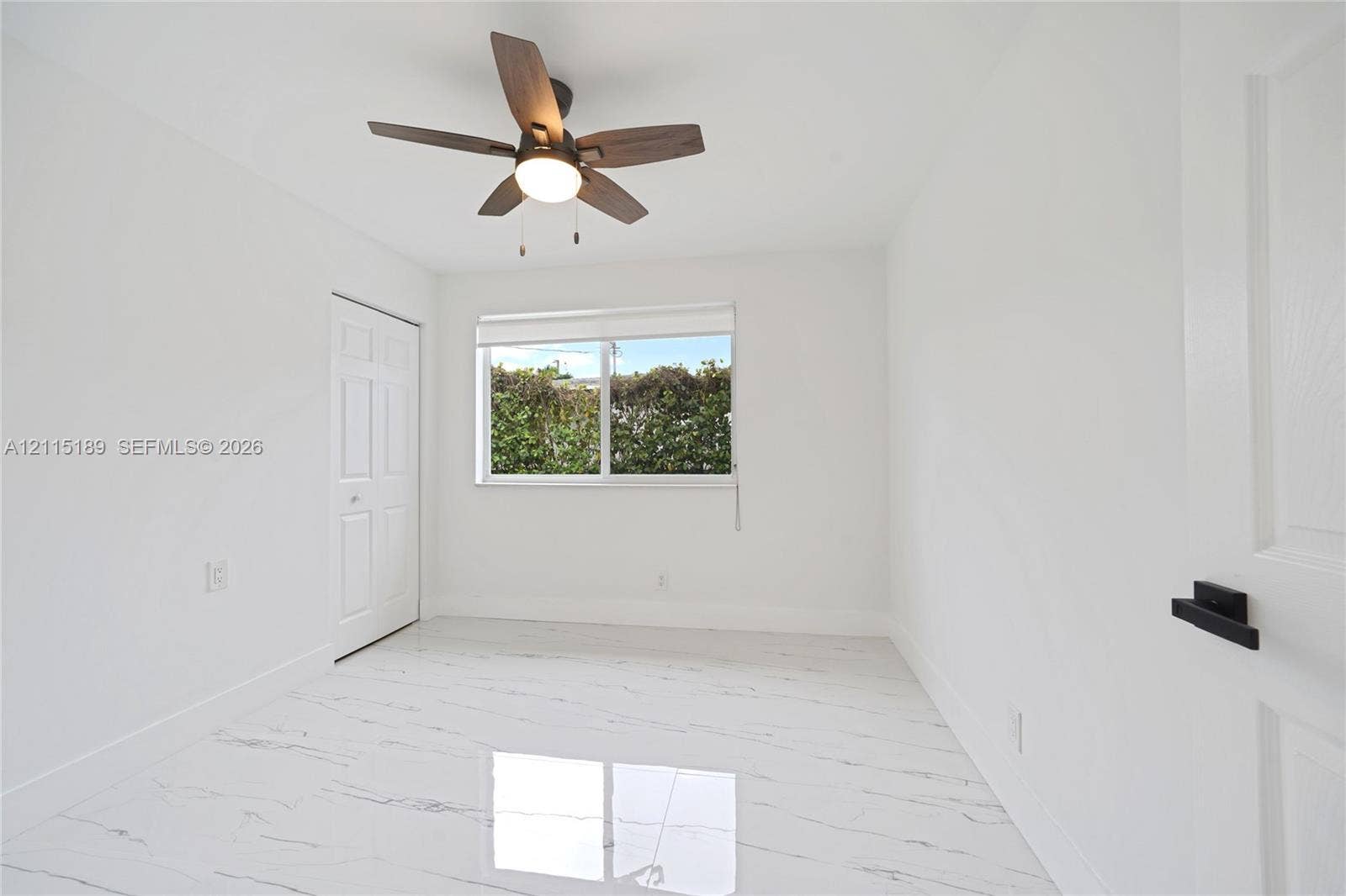2111 N 14th Court, Hollywood, Hollywood, FL 33020 Interior room featuring white-veined tile flooring, a multi-blade ceiling fan with integrated lighting, a sliding window with a roller shade, and doors with matte black hardware