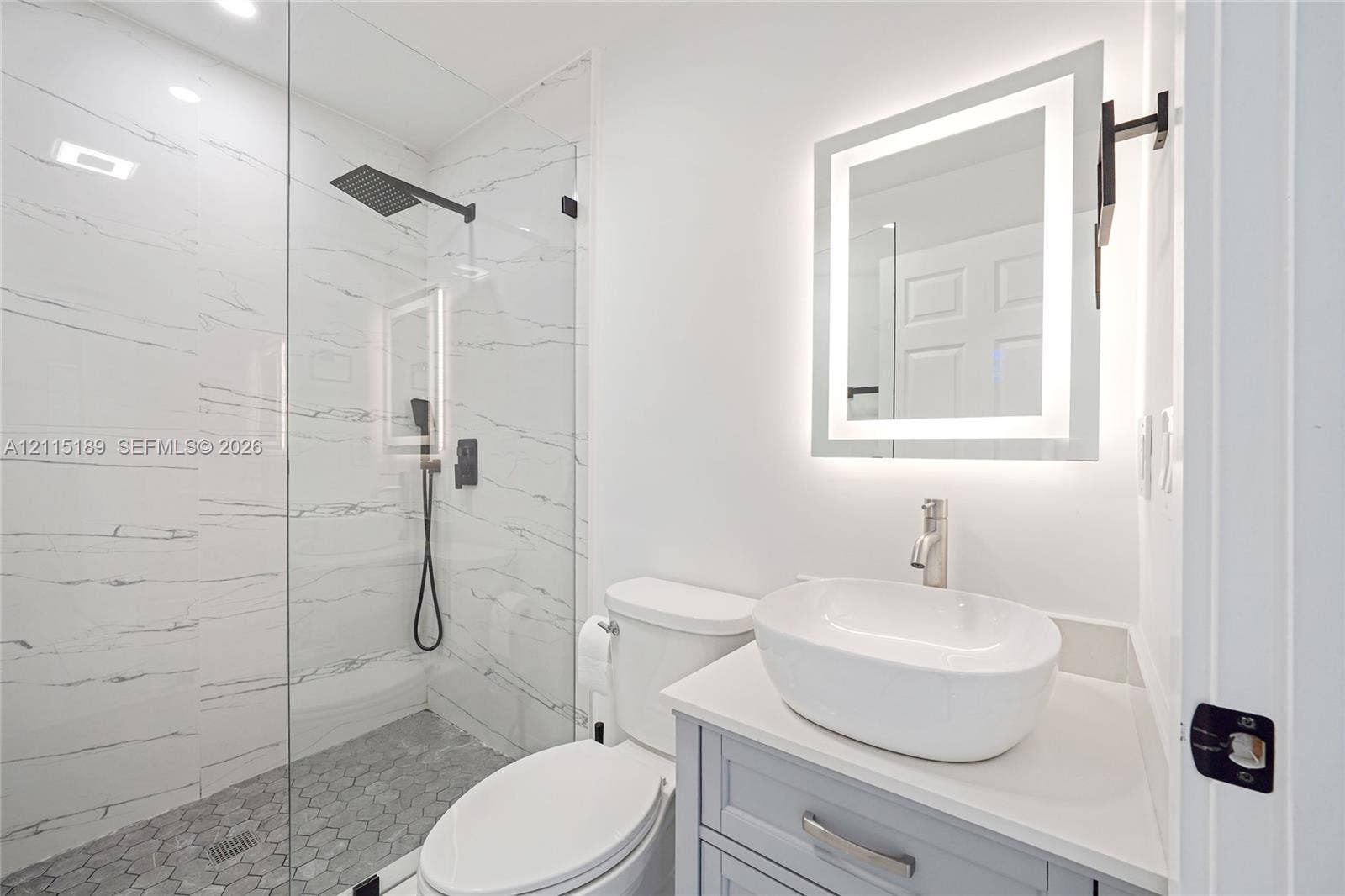2111 N 14th Court, Hollywood, Hollywood, FL 33020 Bathroom featuring a walk-in shower with large-format stone-patterned tile, a frameless glass enclosure, a vessel sink on a vanity with a solid-surface countertop, and an integrated LED-backlit mirror