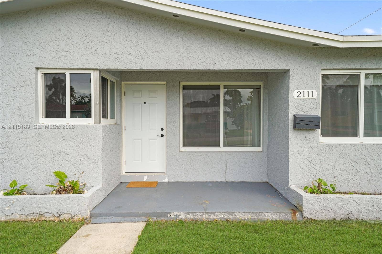 2111 N 14th Court, Hollywood, Hollywood, FL 33020 Stucco exterior featuring a covered entryway, integrated concrete planters, sliding windows, and a multi-pane front door