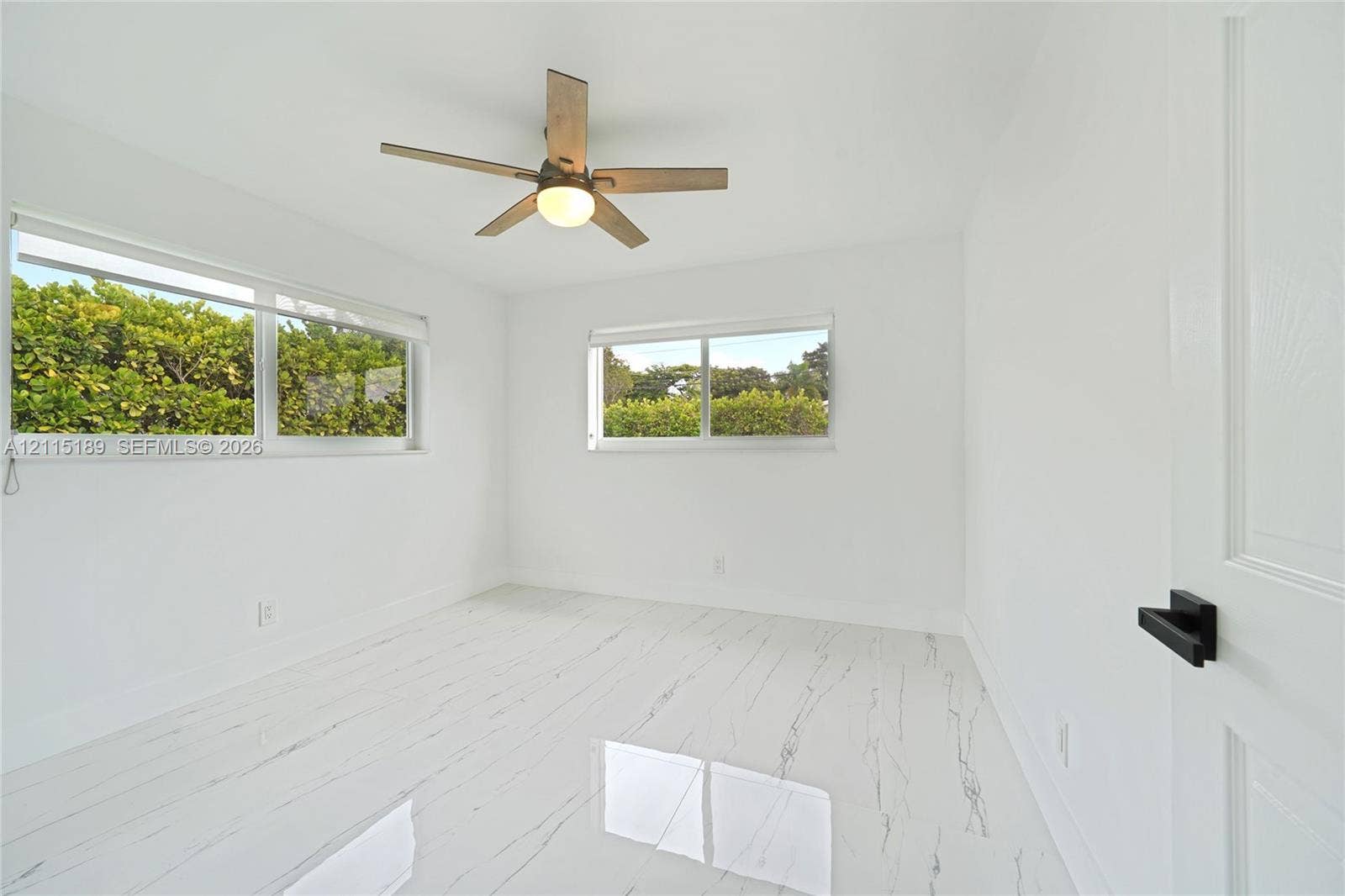 2111 N 14th Court, Hollywood, Hollywood, FL 33020 Room featuring polished white tile flooring with veining, large horizontal windows, a wooden-finish ceiling fan with integrated lighting, and a door with matte black hardware
