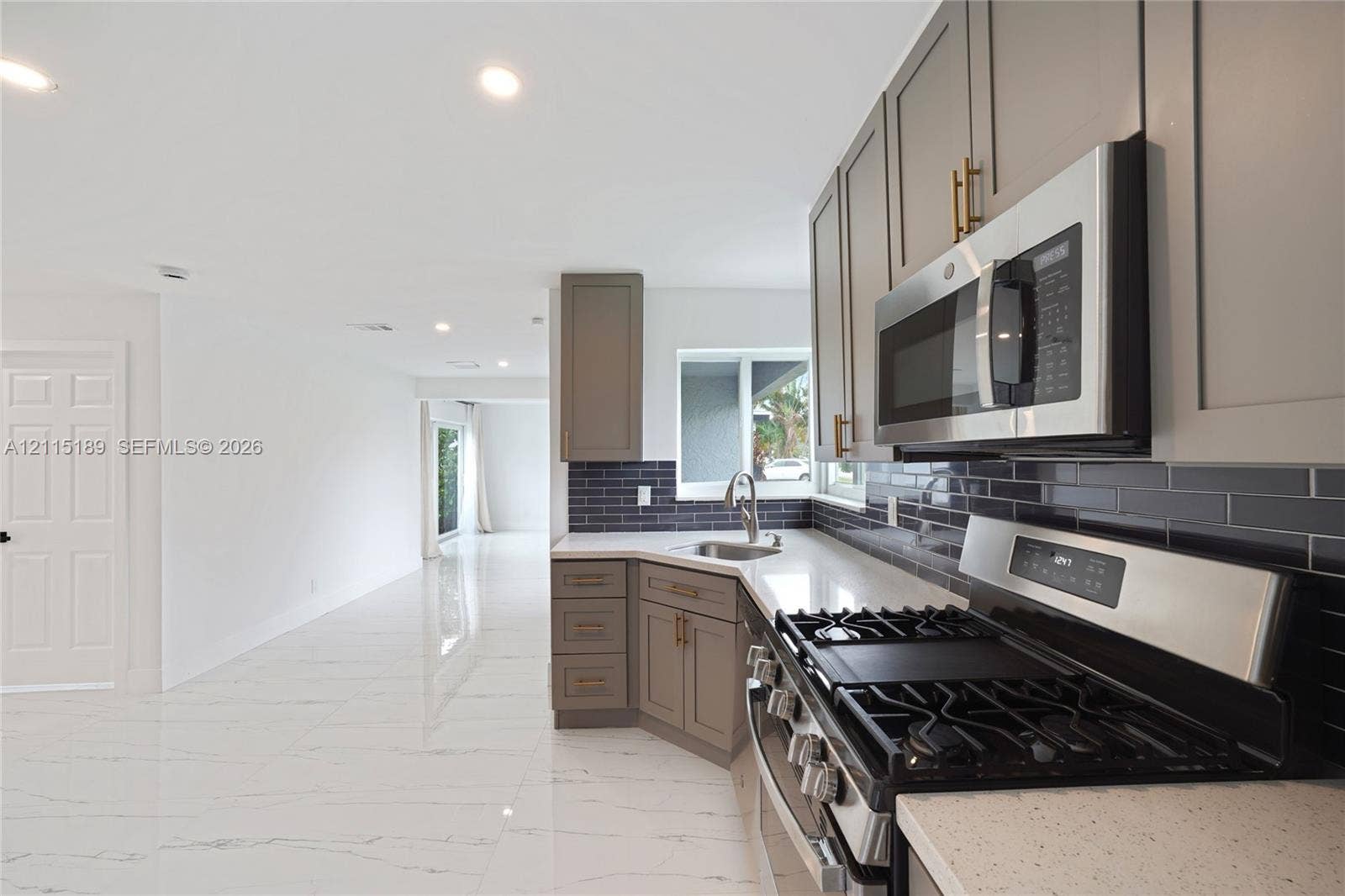 2111 N 14th Court, Hollywood, Hollywood, FL 33020 Kitchen featuring grey Shaker-style cabinetry, quartz countertops, a dark subway tile backsplash, stainless steel appliances, and large-format tile flooring