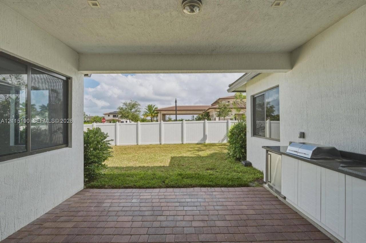 Covered patio with outdoor kitchen and built-in grill.
