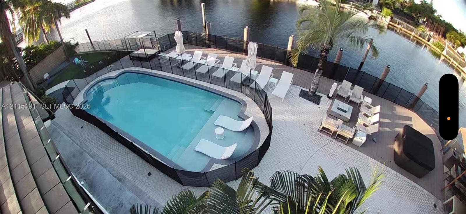 451 Center Island Drive, Golden Beach, FL 33160 Waterfront pool area featuring a built-in sun shelf, perimeter safety fencing, paved patio, and dockage