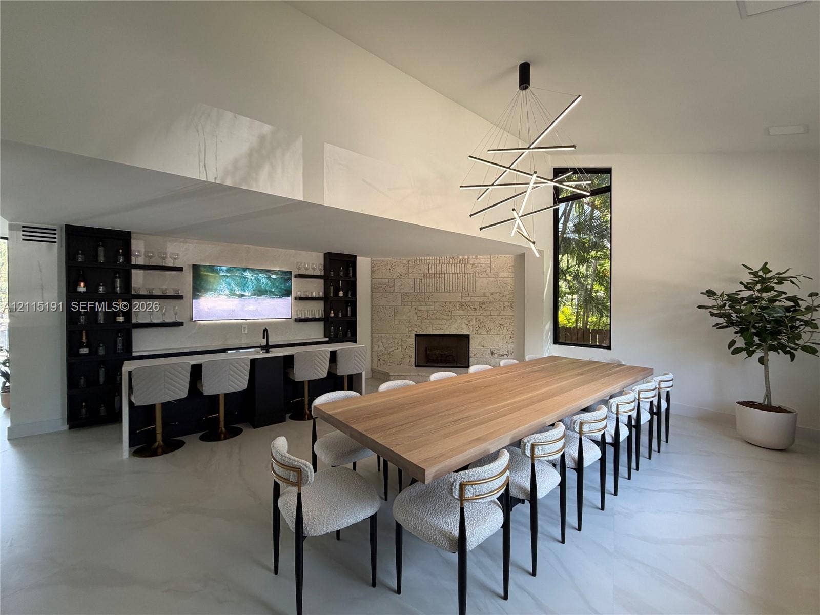 451 Center Island Drive, Golden Beach, FL 33160 Built-in wet bar with dark cabinetry, floating shelving, and integrated sink, stone-faced fireplace, modern geometric chandelier, and large-format flooring