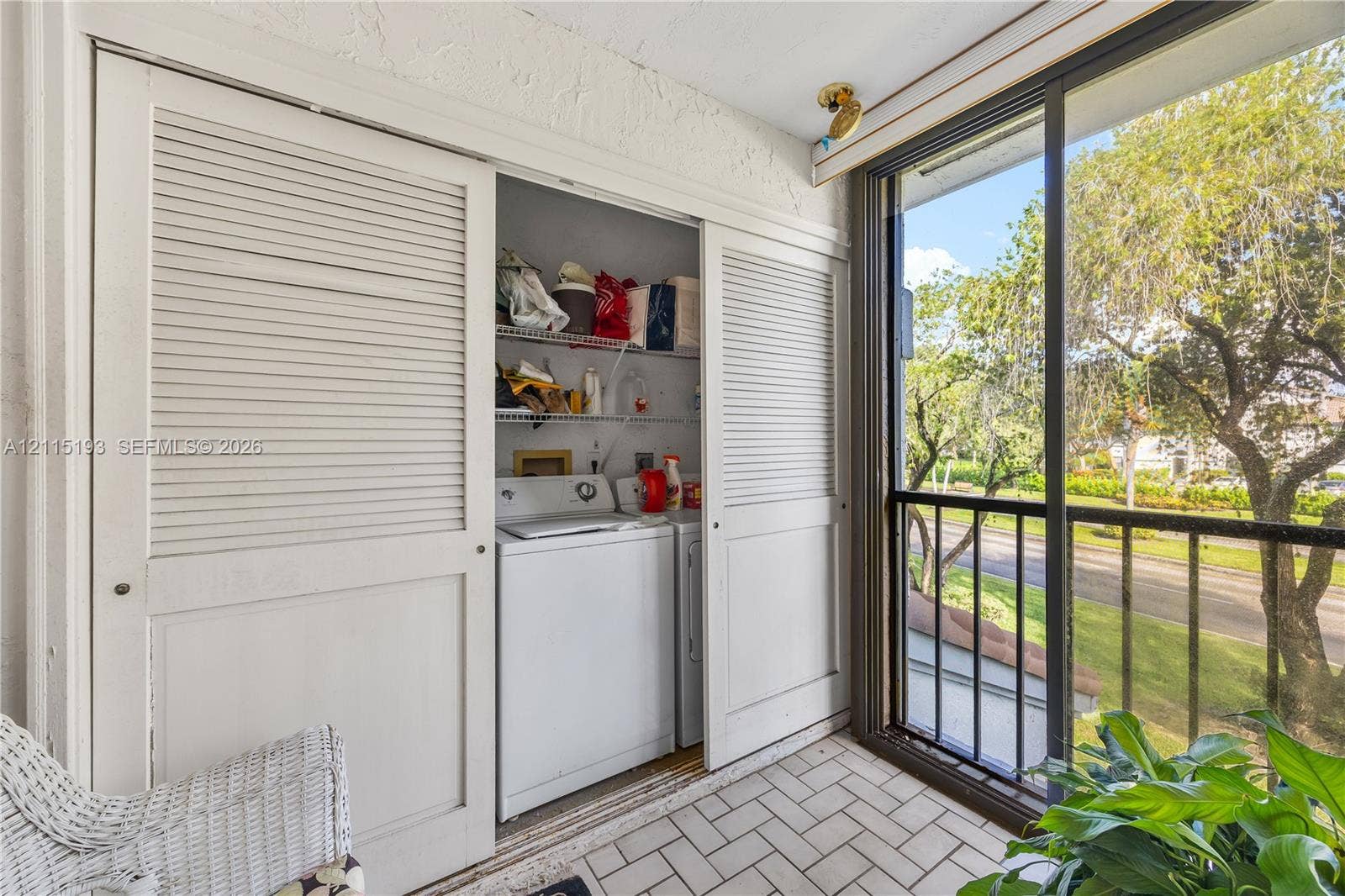 5422 Venetia Court, #G, Boynton Beach, FL 33437 Enclosed balcony featuring a tile floor, white louvered sliding closet doors, built-in wire shelving, and floor-to-ceiling glass sliding doors with metal frame
