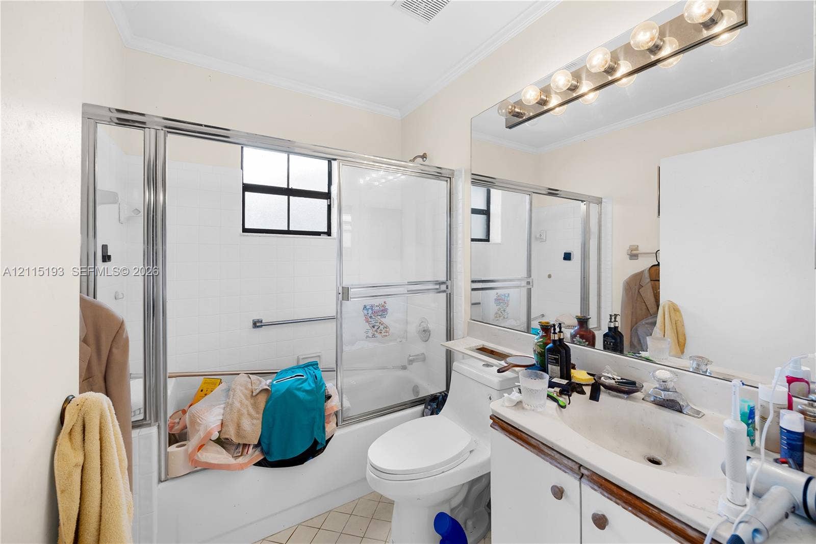 5422 Venetia Court, #G, Boynton Beach, FL 33437 Bathroom featuring a white vanity with a composite countertop, large wall-mounted mirror, multi-bulb vanity light, and a tub-shower combination with a glass sliding enclosure