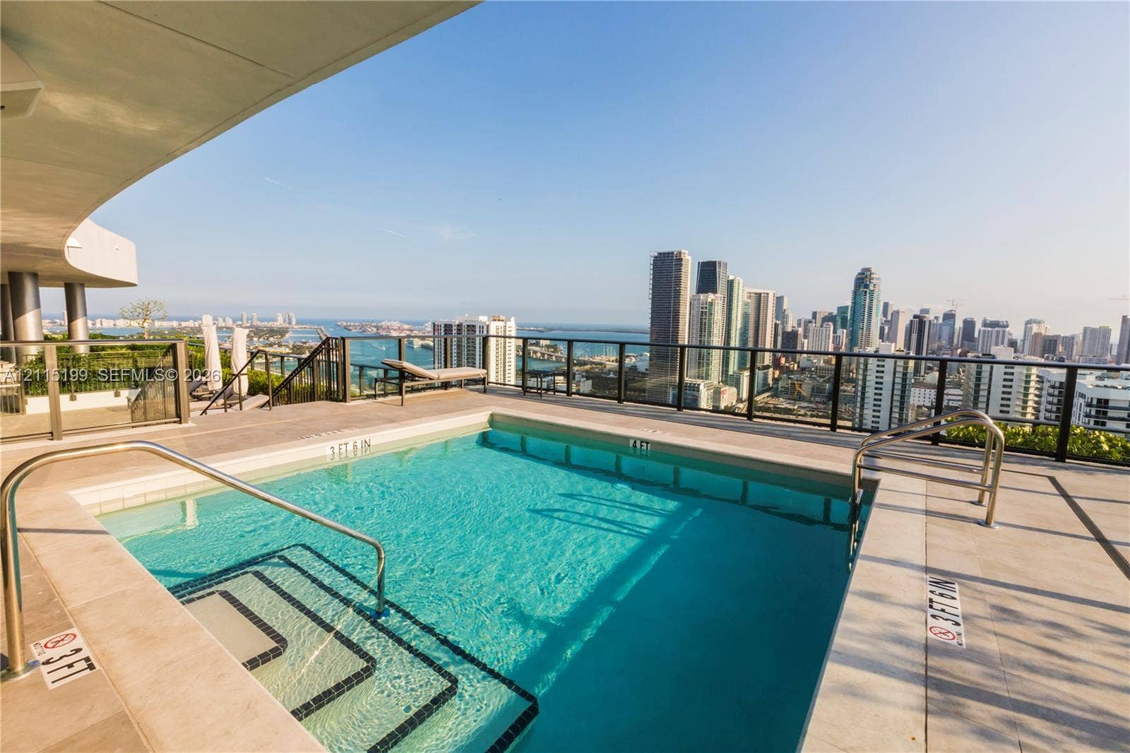 1600 NE 1st Avenue, #3120, Miami, FL 33132 Rooftop swimming pool featuring stone tile decking, stainless steel handrails, a glass panel perimeter railing, and a cityscape backdrop