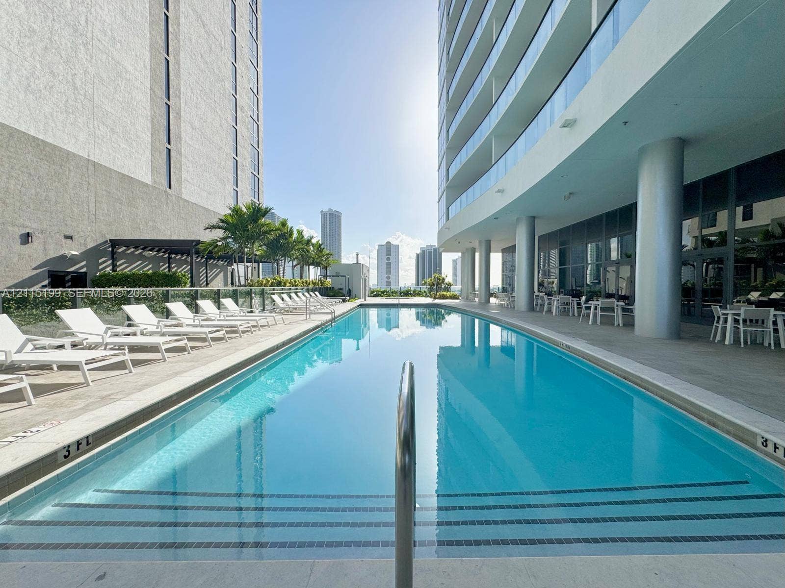 1600 NE 1st Avenue, #3120, Miami, FL 33132 Rectangular swimming pool with tiled entry steps, expansive stone-paved pool deck, glass balcony railings, and structural columns