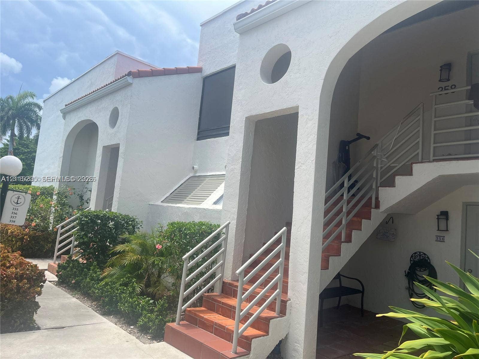 Stucco exterior featuring arched entryways, circular accent windows, terracotta-tile stairs.