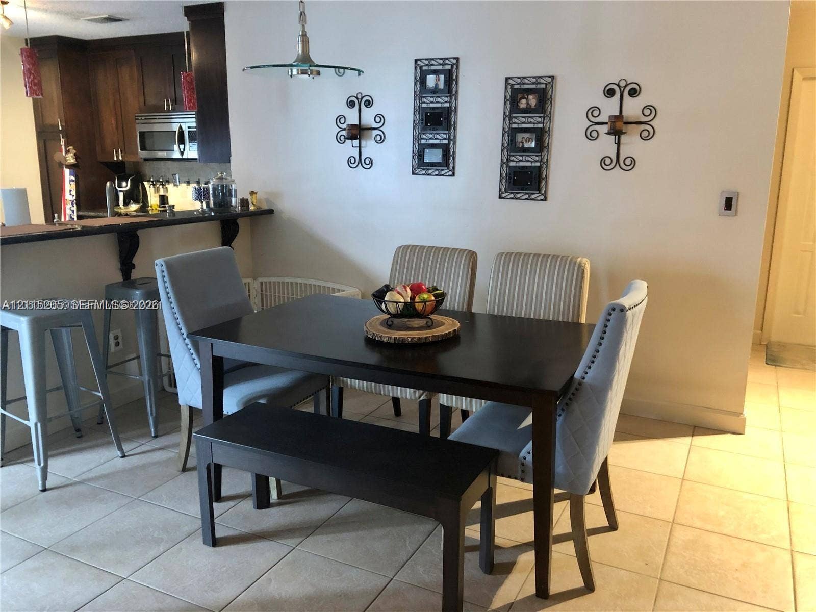 Dining area featuring tile flooring, a breakfast bar with stone-style countertop pass through.