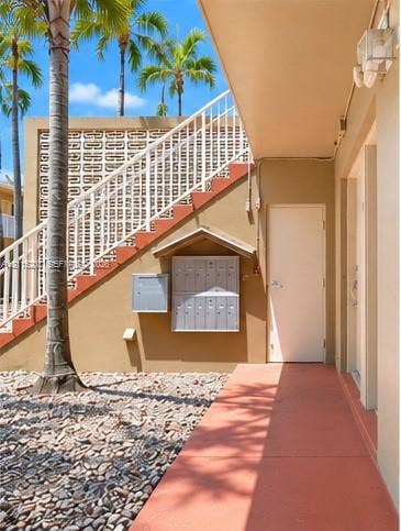 6330 SW 79th Street, #20, South Miami, South Miami, FL 33143 Exterior space featuring a concrete staircase with metal railings, decorative breeze block screening, built-in metal mailboxes, and paved ground cover