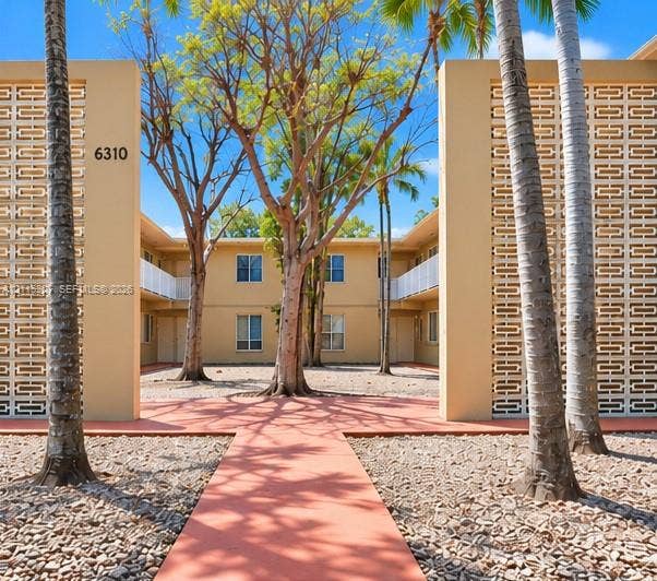 6330 SW 79th Street, #20, South Miami, South Miami, FL 33143 Mid-century exterior featuring decorative breeze block screening, a paved central courtyard walkway, and mature palms