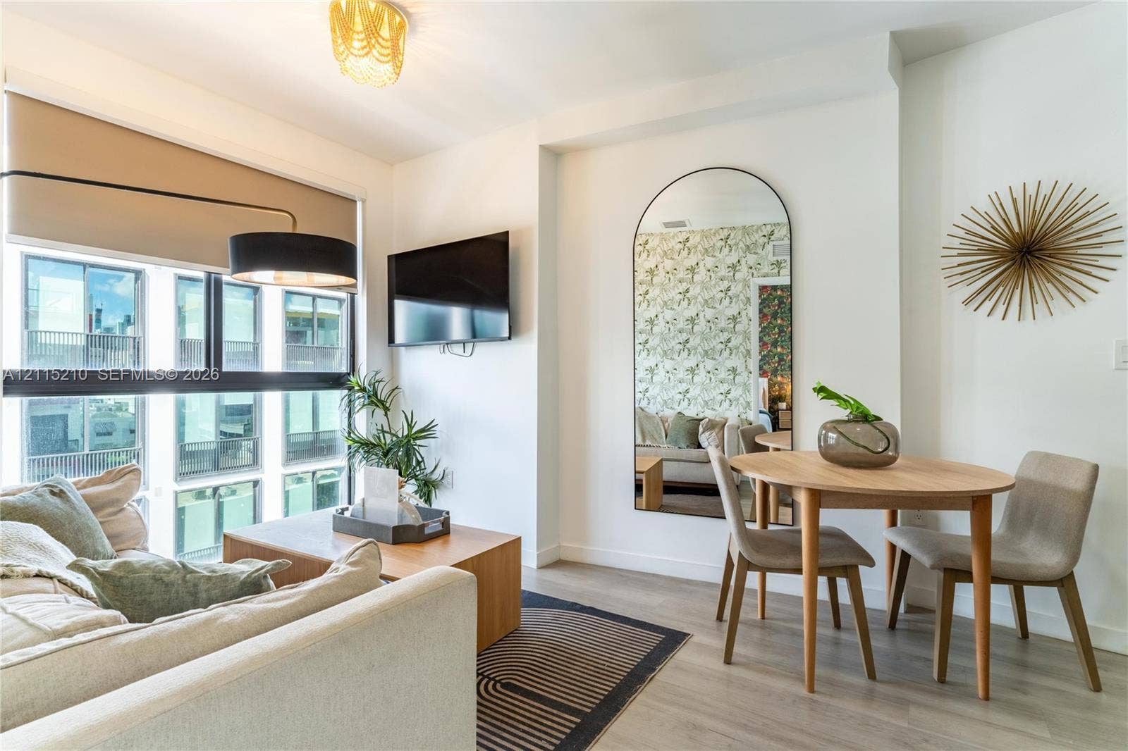 136 NW 26th Street, #507, Miami, FL 33127 Floor-to-ceiling windows, wood-finish flooring, built-in television mount, and full-length arched wall mirror