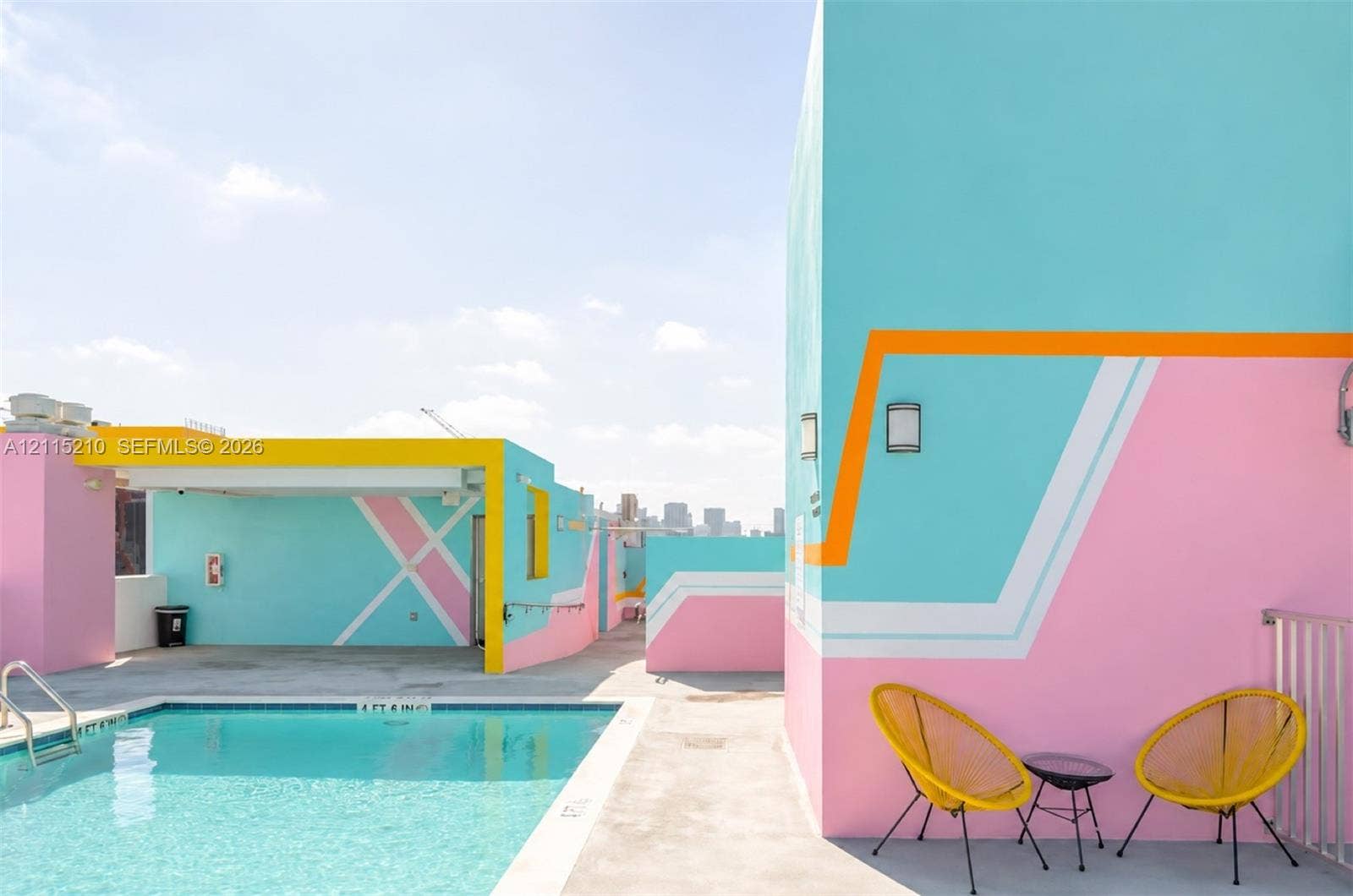 136 NW 26th Street, #507, Miami, FL 33127 Rooftop terrace featuring an in-ground swimming pool, smooth concrete decking, geometric wall murals, and metallic perimeter railings